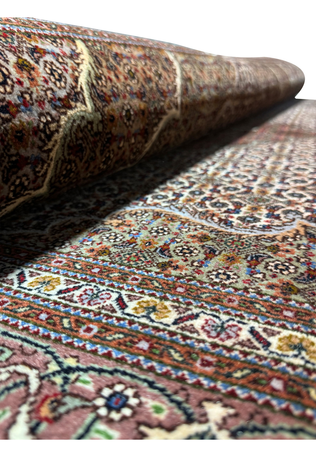 Perspective view of a rolled 5x7 Persian Tabriz Mahi rug, highlighting the tight weave and plush pile, with intricate patterns peeking from the inner layers.