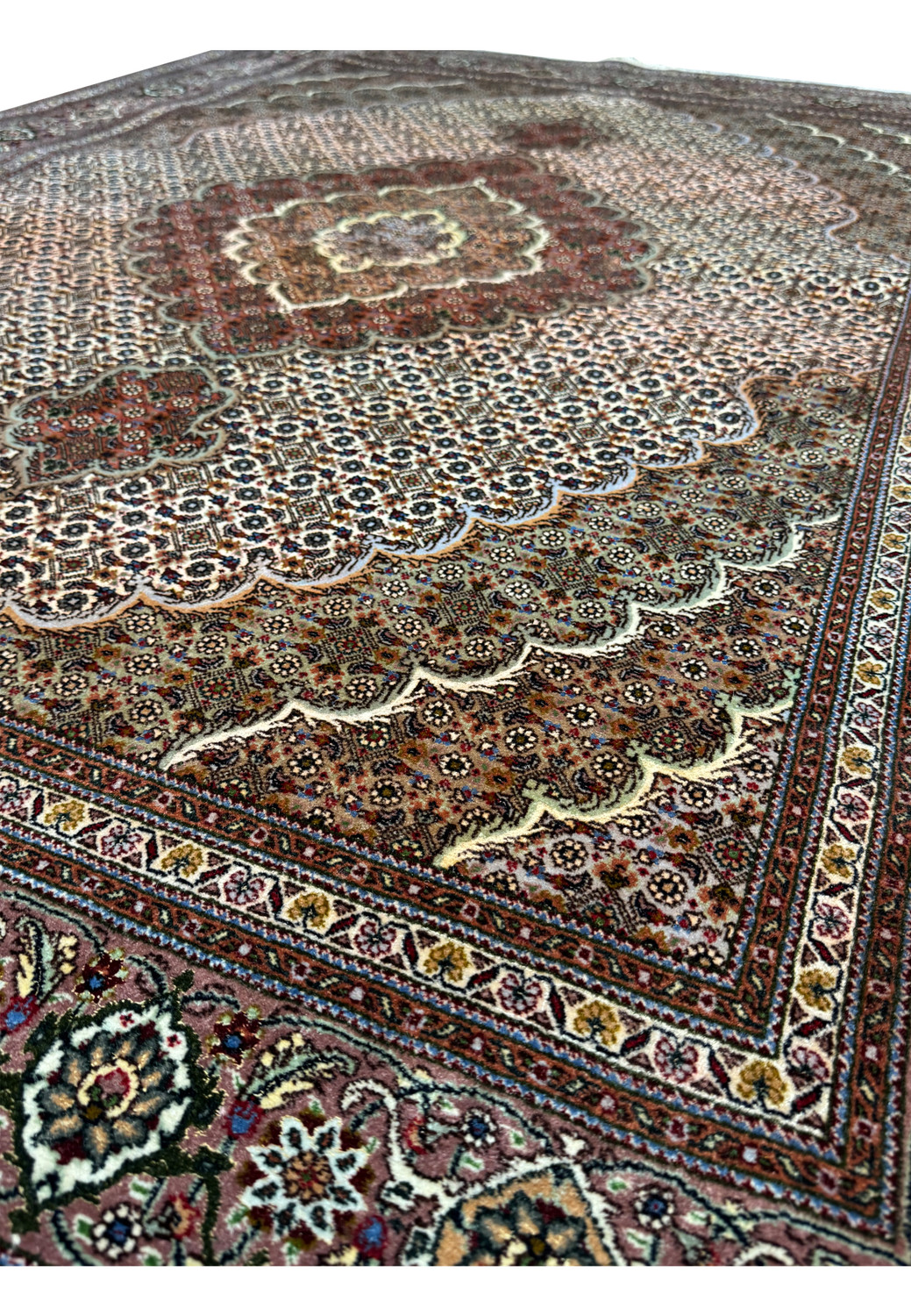 Angled perspective of the 5x7 Persian Tabriz Mahi rug showing the texture and weave of the rug's pile, with a focus on the central design flowing into the border.