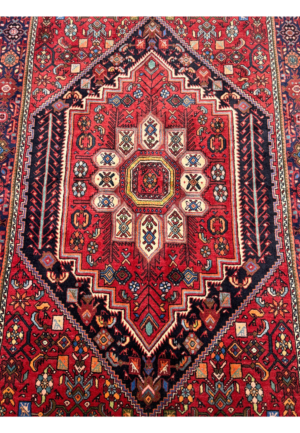 Close-up on the full display of a Persian Gholotgh Rug, highlighting the detailed craftsmanship and rich color scheme with dominant red hues