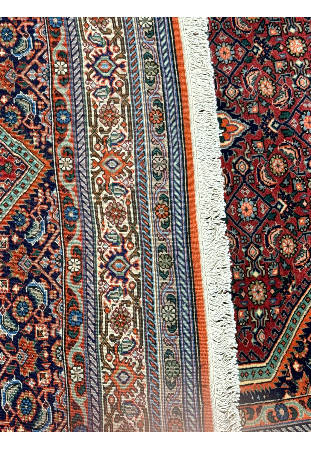 A close-up view of the side border of the Persian Bijar rug, showcasing the detailed geometric and floral patterns against a red backdrop.