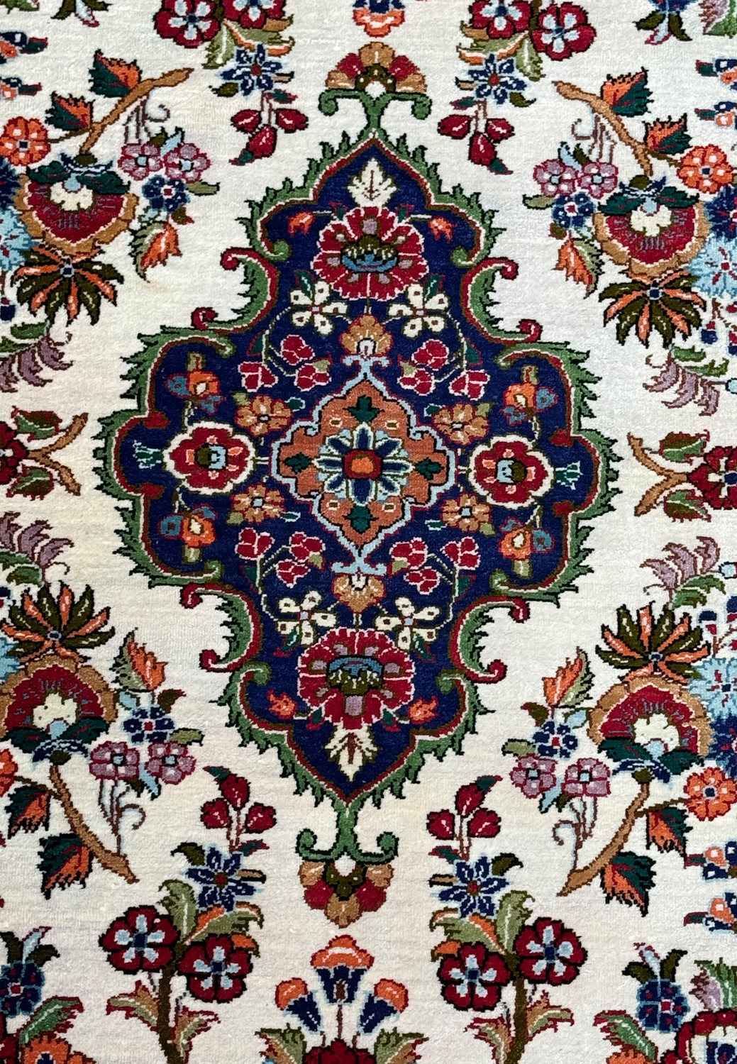 Close-up of the central medallion on a Persian Qum silk rug, highlighting the detailed weaving and color contrast.