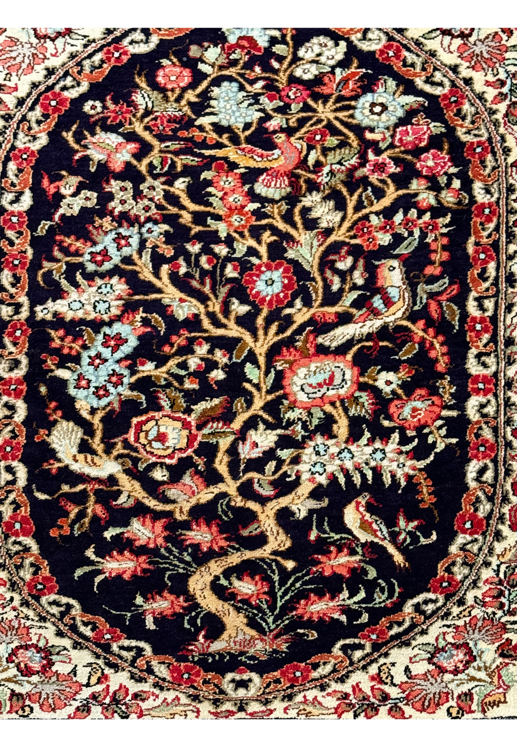 Detailed image focusing on the central tree-of-life motif surrounded by floral accents on a Persian Qum silk rug