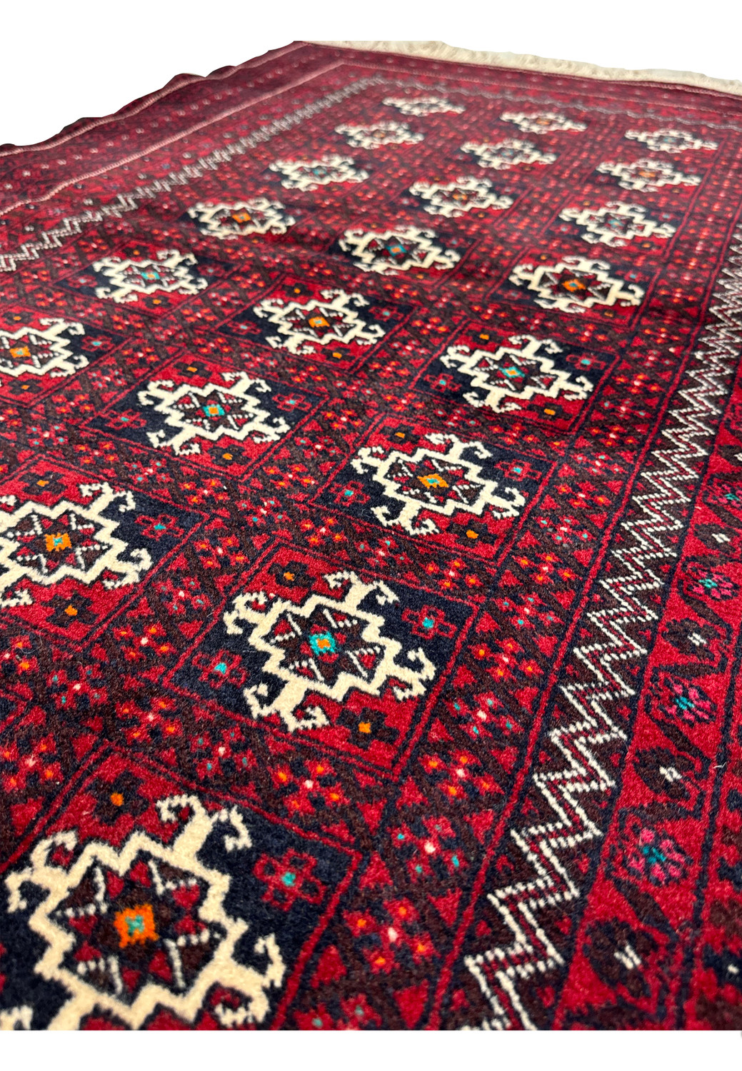 Persian Baluch rug detail highlighting the symmetry of geometric designs and the vibrant contrast of dark red and white elements