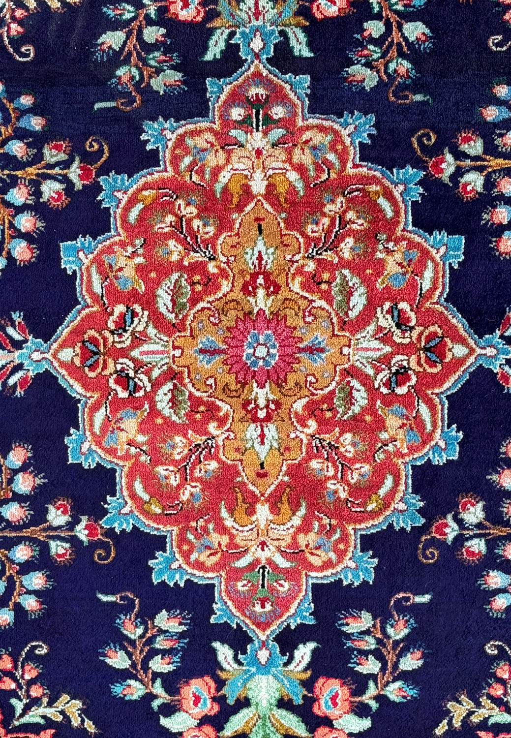 Detailed view of the lush floral patterns and gold accents on the rich navy blue field of a Persian Qum silk rug