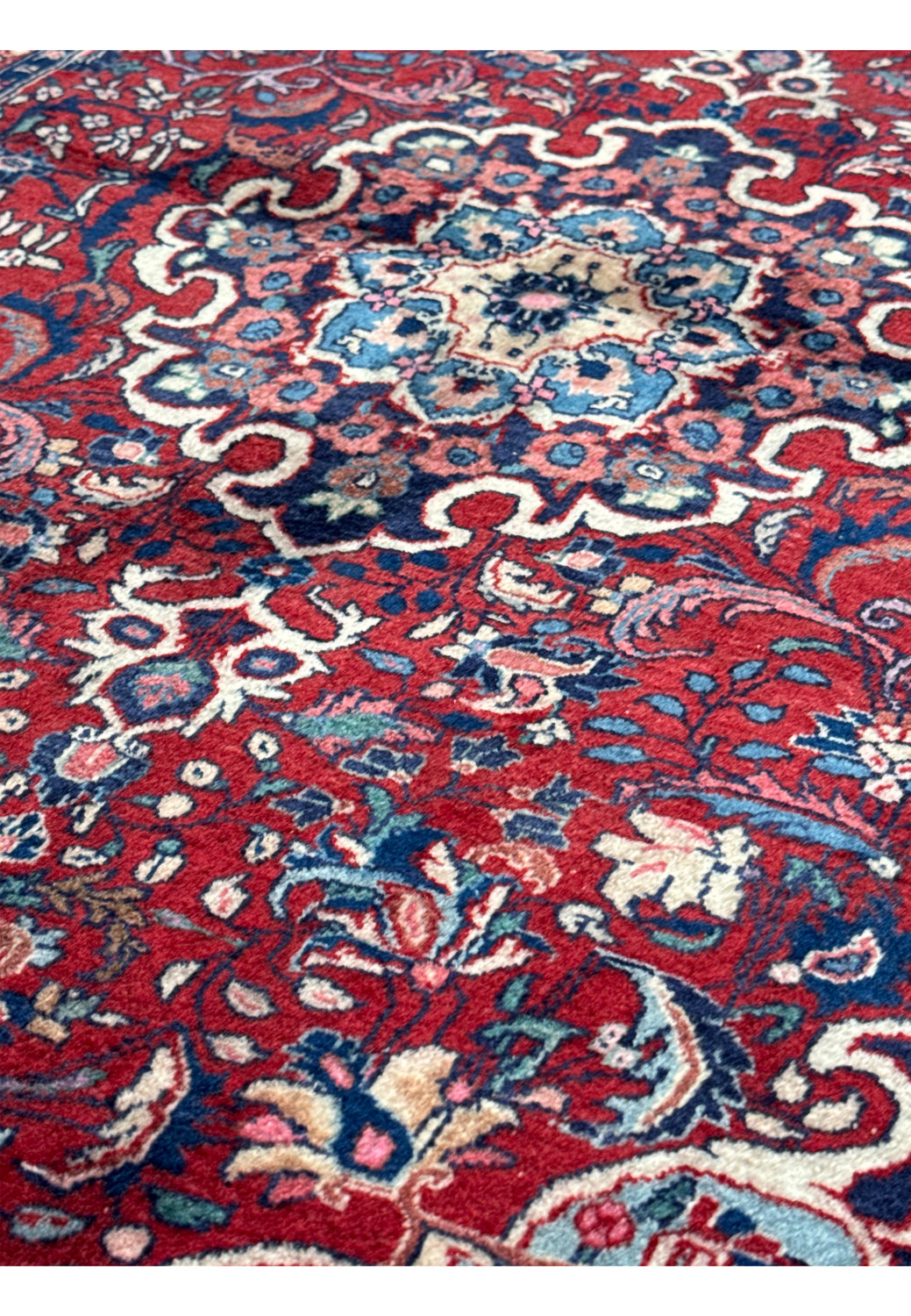 Close-up view of the Persian Sarough rug's dense weave and plush pile, with floral patterns and dark spots due to shimmering wool.