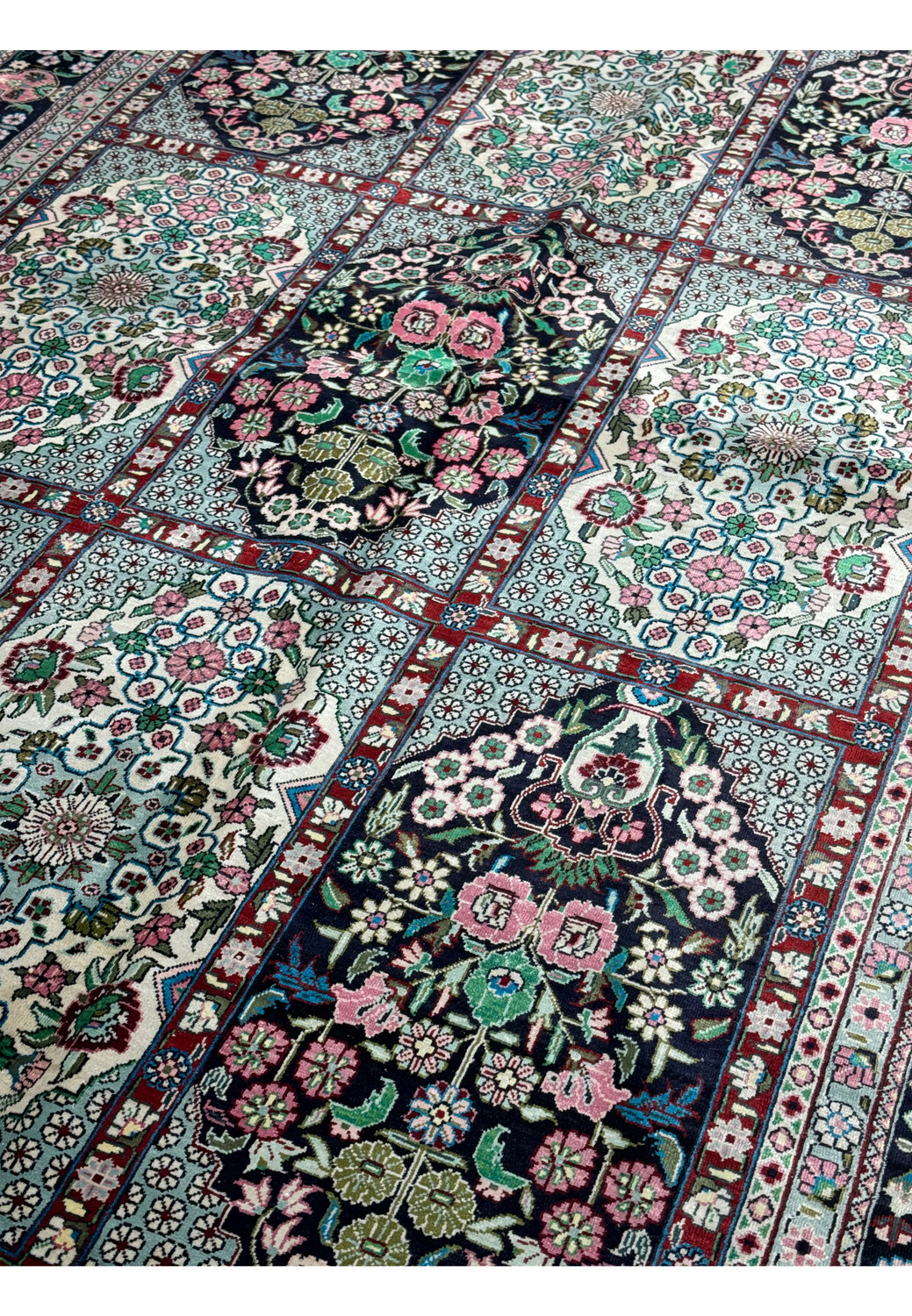 Edge-to-edge view of a Persian Qum silk rug, featuring complex floral motifs and a traditional design