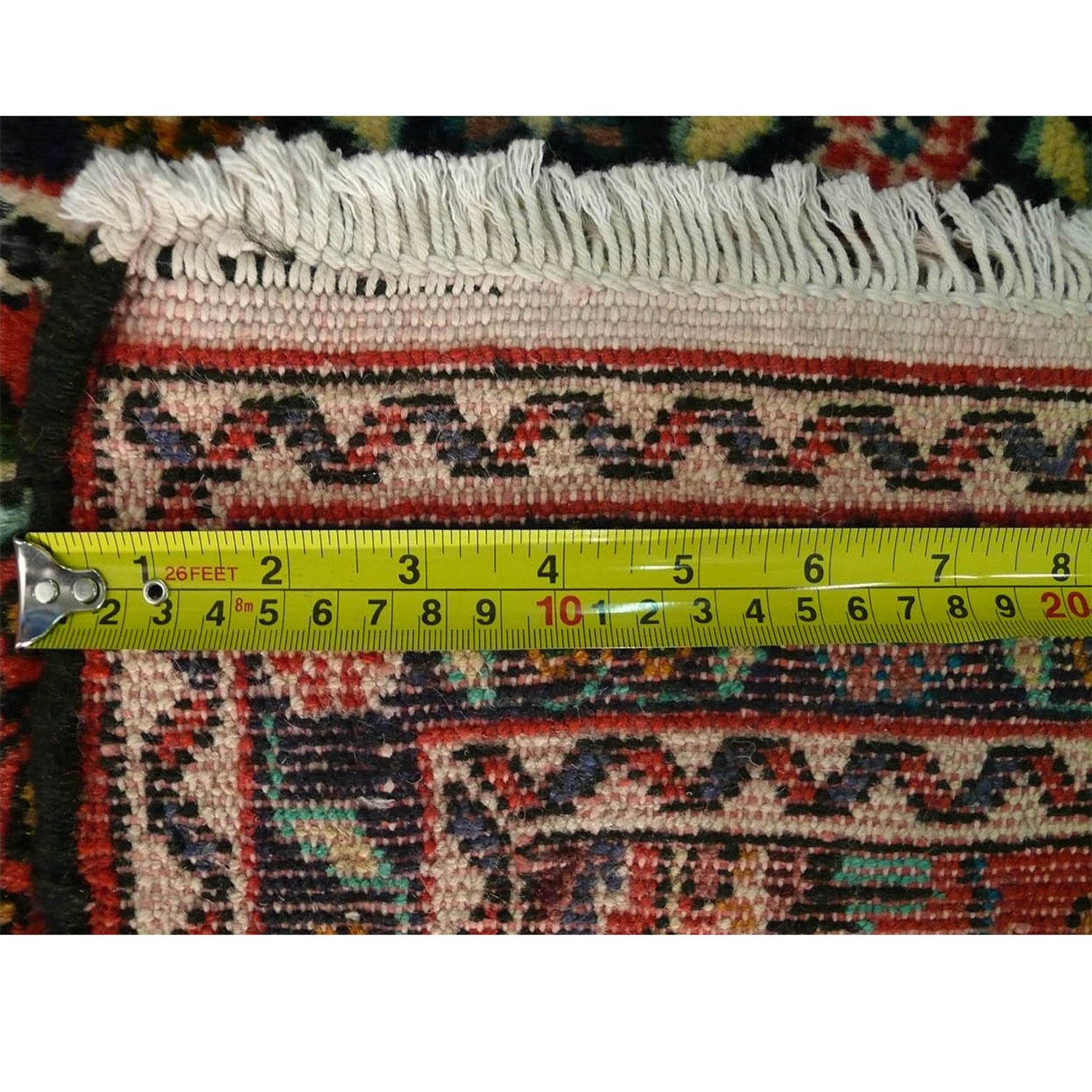 A picture displaying a measuring tape along the fringe of the Persian Darjazin runner rug, detailing the precision of its craftsmanship.