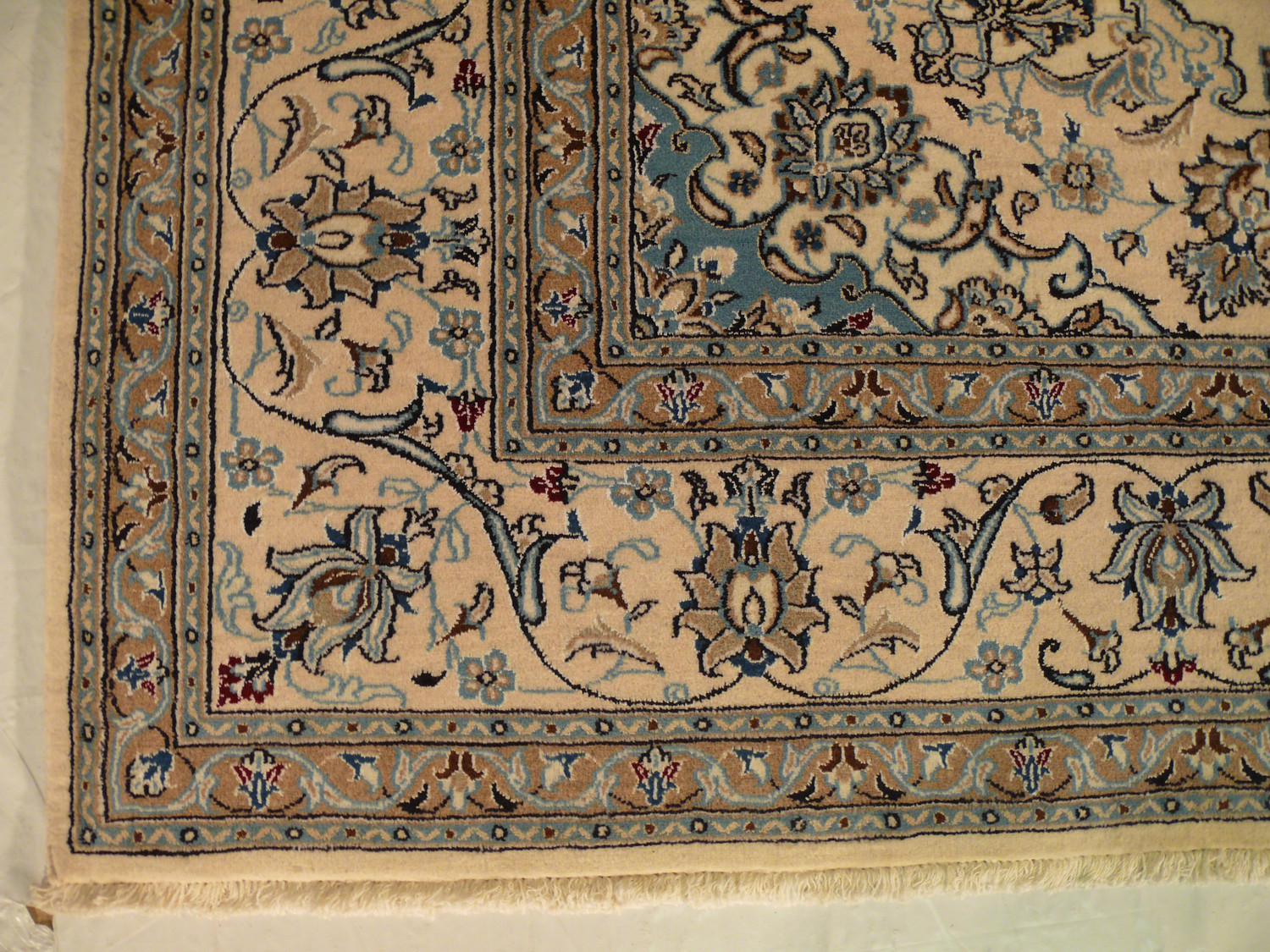 Border detail showing layered navy, grey, and light brown floral motifs on Persian Nain rug Border detail showing layered navy, grey, and light brown floral motifs on Persian Nain rug