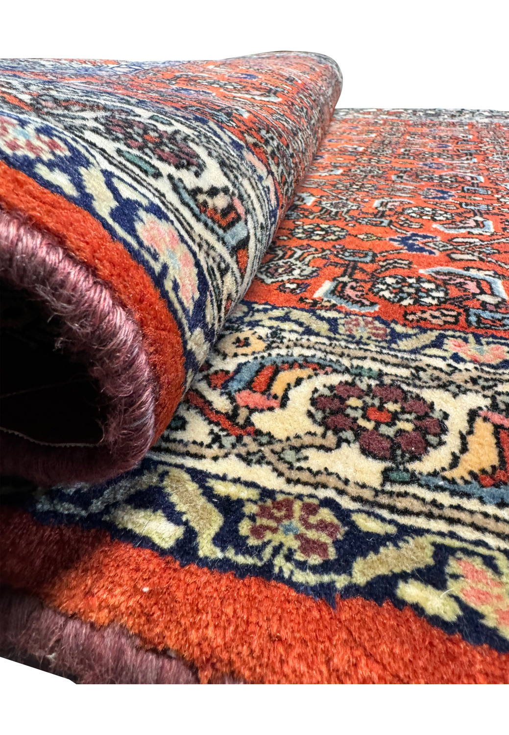 A close view of the Bijar rug rolled up, revealing the texture and pattern continuity across the weave.