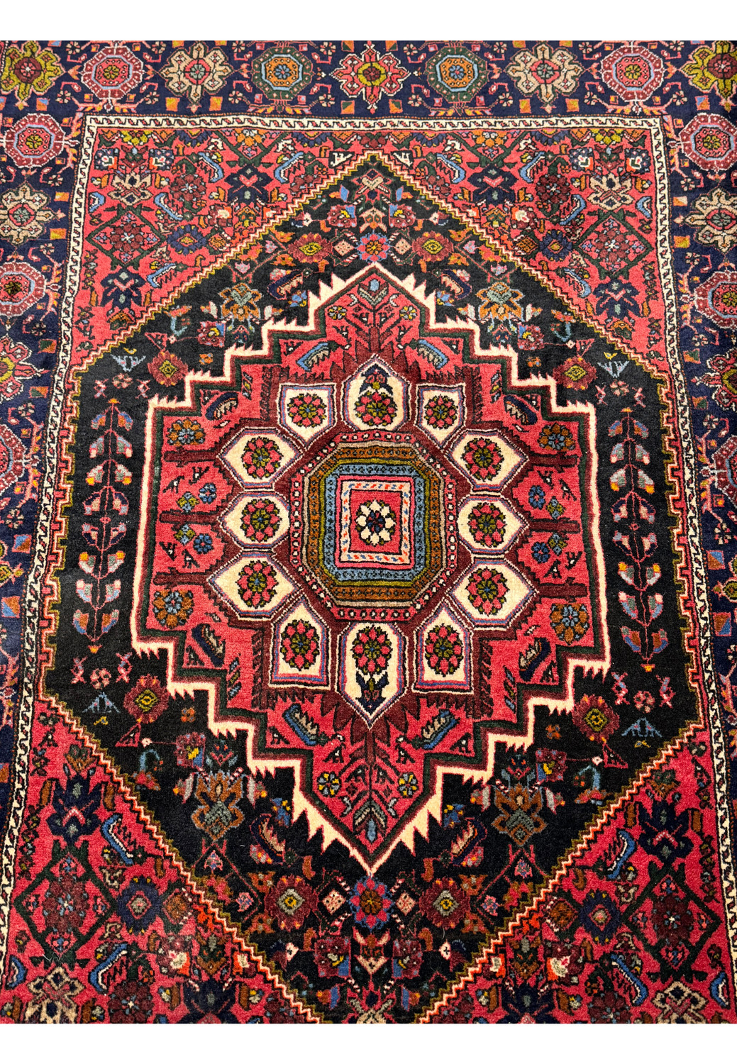 Full view of a Persian Gholtogh rug on the floor, showcasing the complex design and traditional motifs.