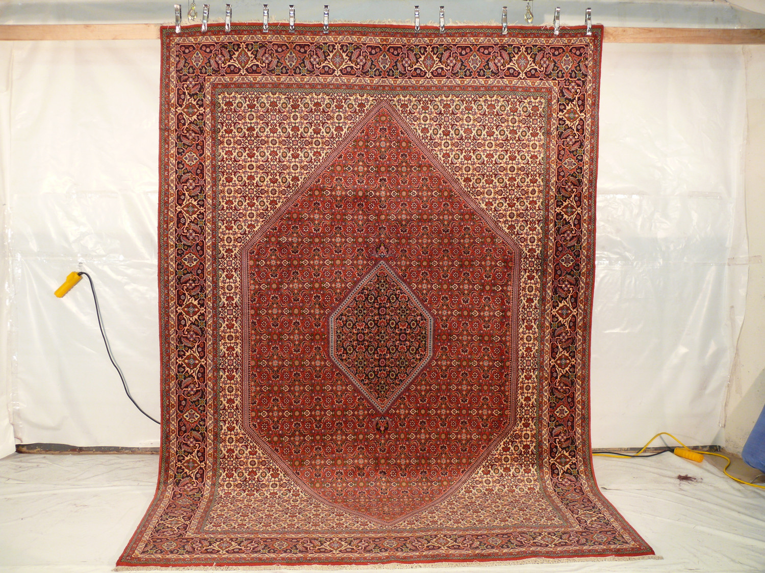 Persian Bijar rug hanging vertically, displaying its full length and the detailed craftsmanship of the patterns