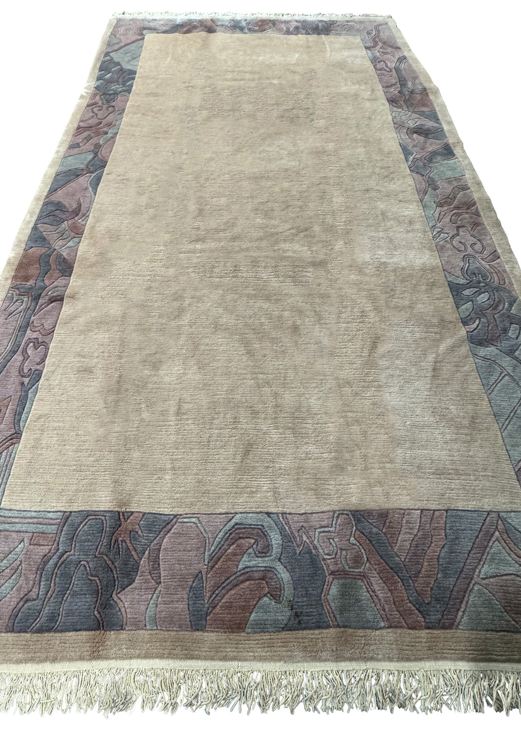 Angled full view of a Modern Royal Tibetan beige rug displaying the patterned border and fringe.