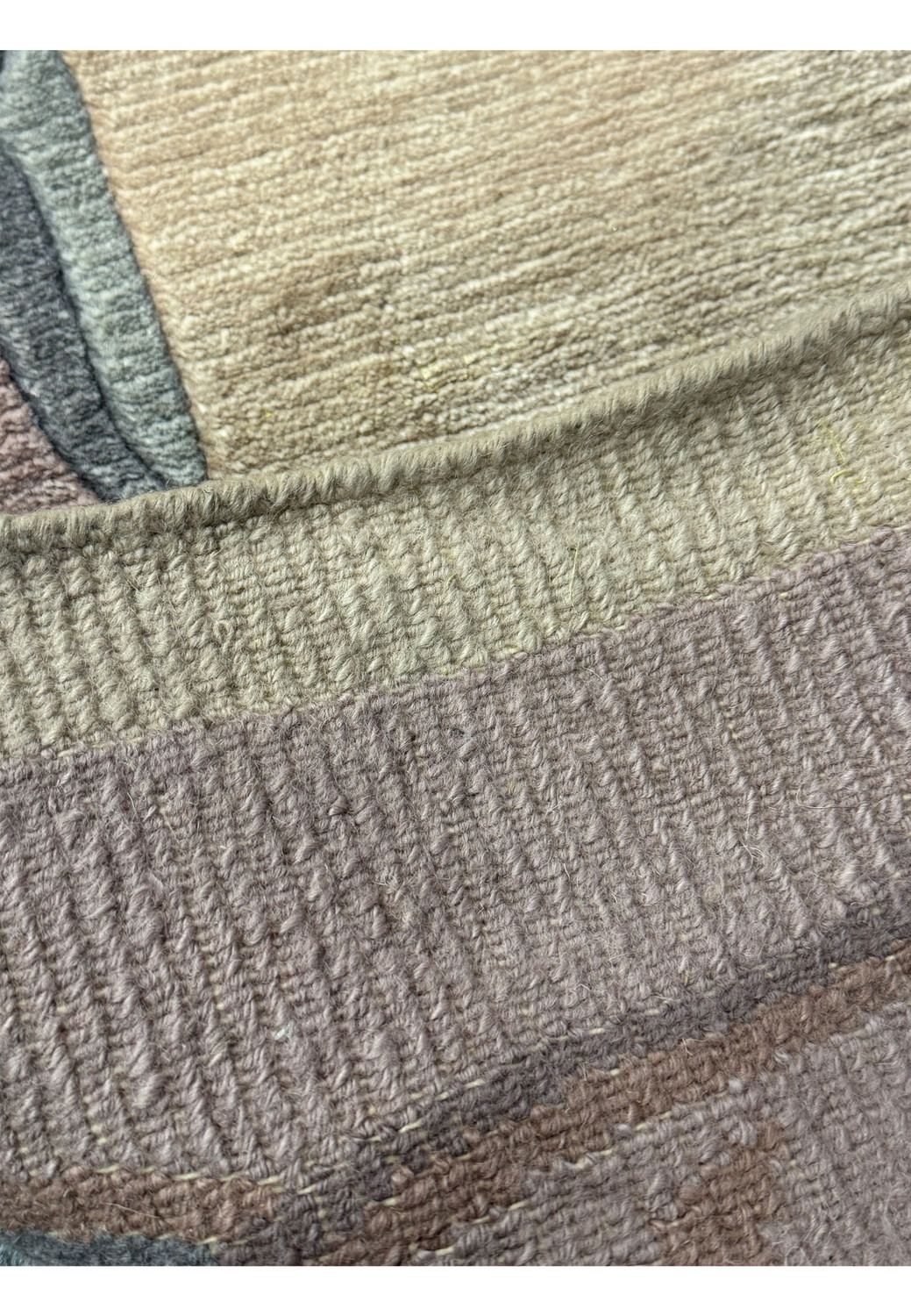 Close-up on the Modern Royal Tibetan rug's texture and subtle color variation in natural light. Showing the back of the rug to illustrate the professional handmade weaving technique