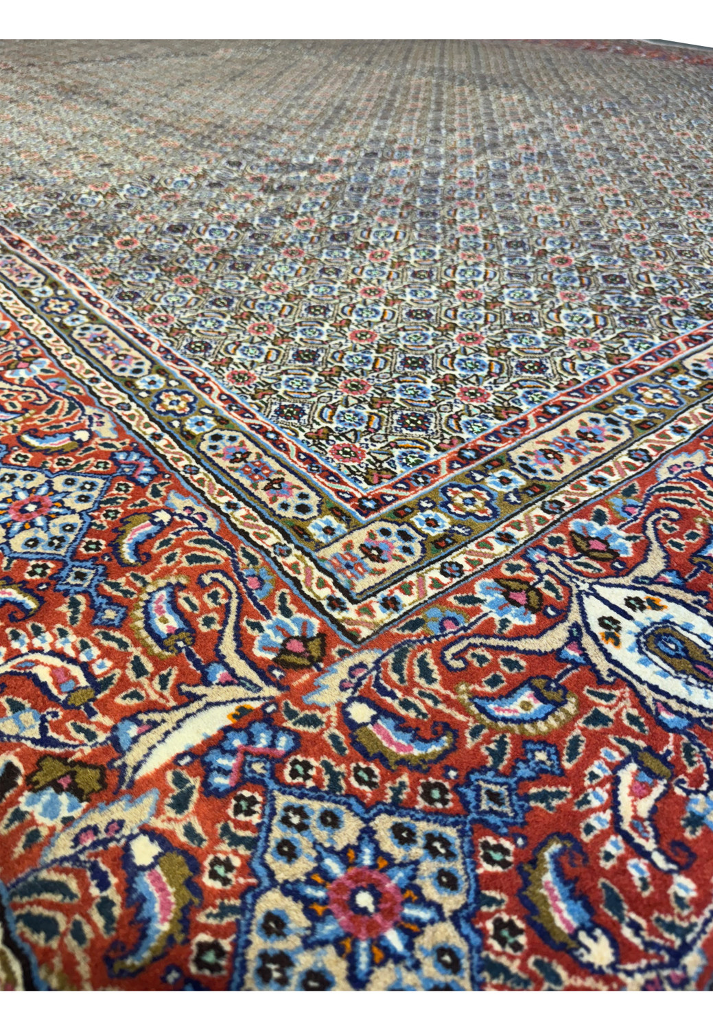 An angled close-up of the Persian Moud Rug's edge, exhibiting the detailed patterns and the vibrant contrast of colors.
