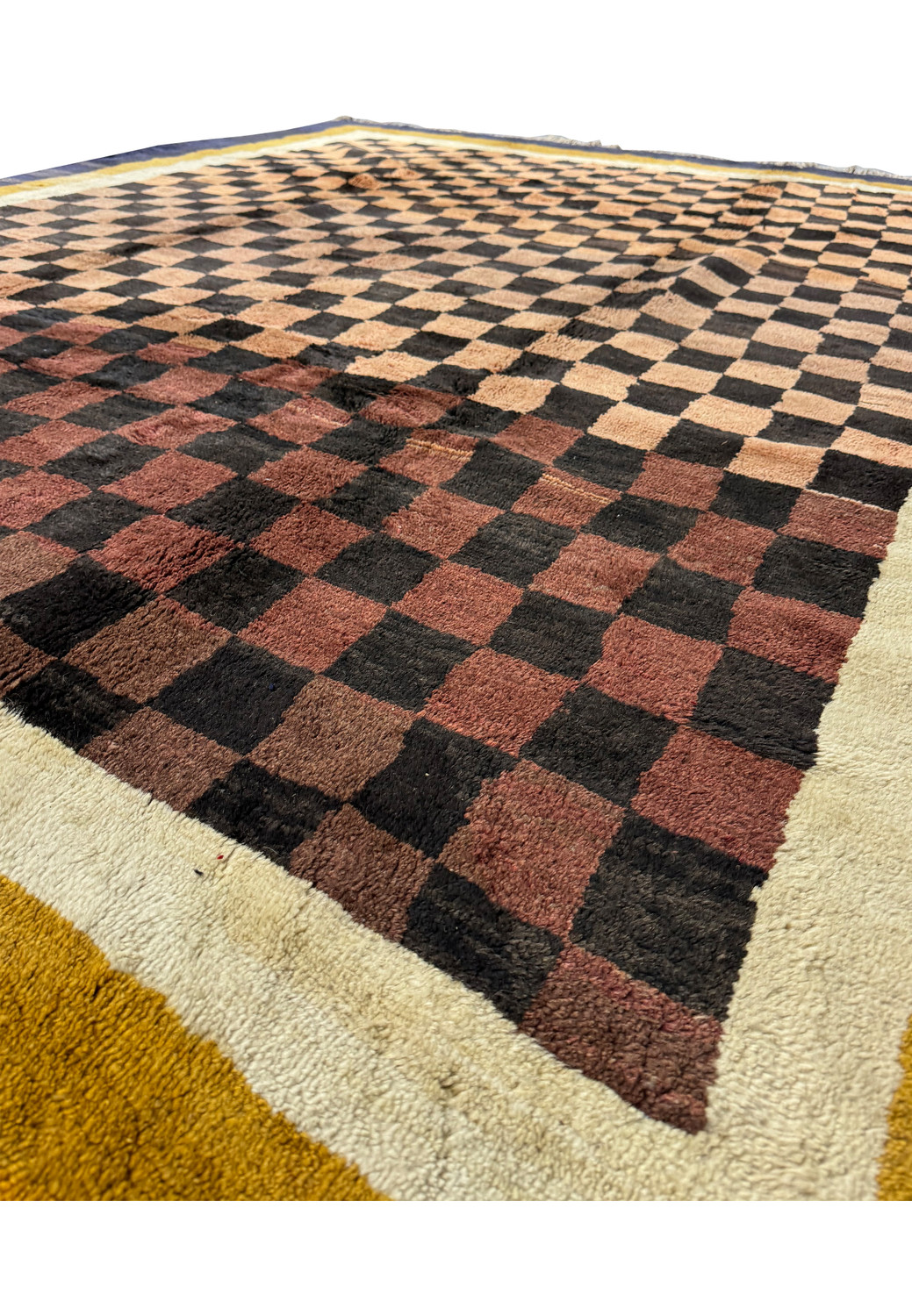 Angled view of a modern Nepal rug with a 3D checkerboard pattern in shades of brown and beige, bordered by deep indigo and golden yellow.