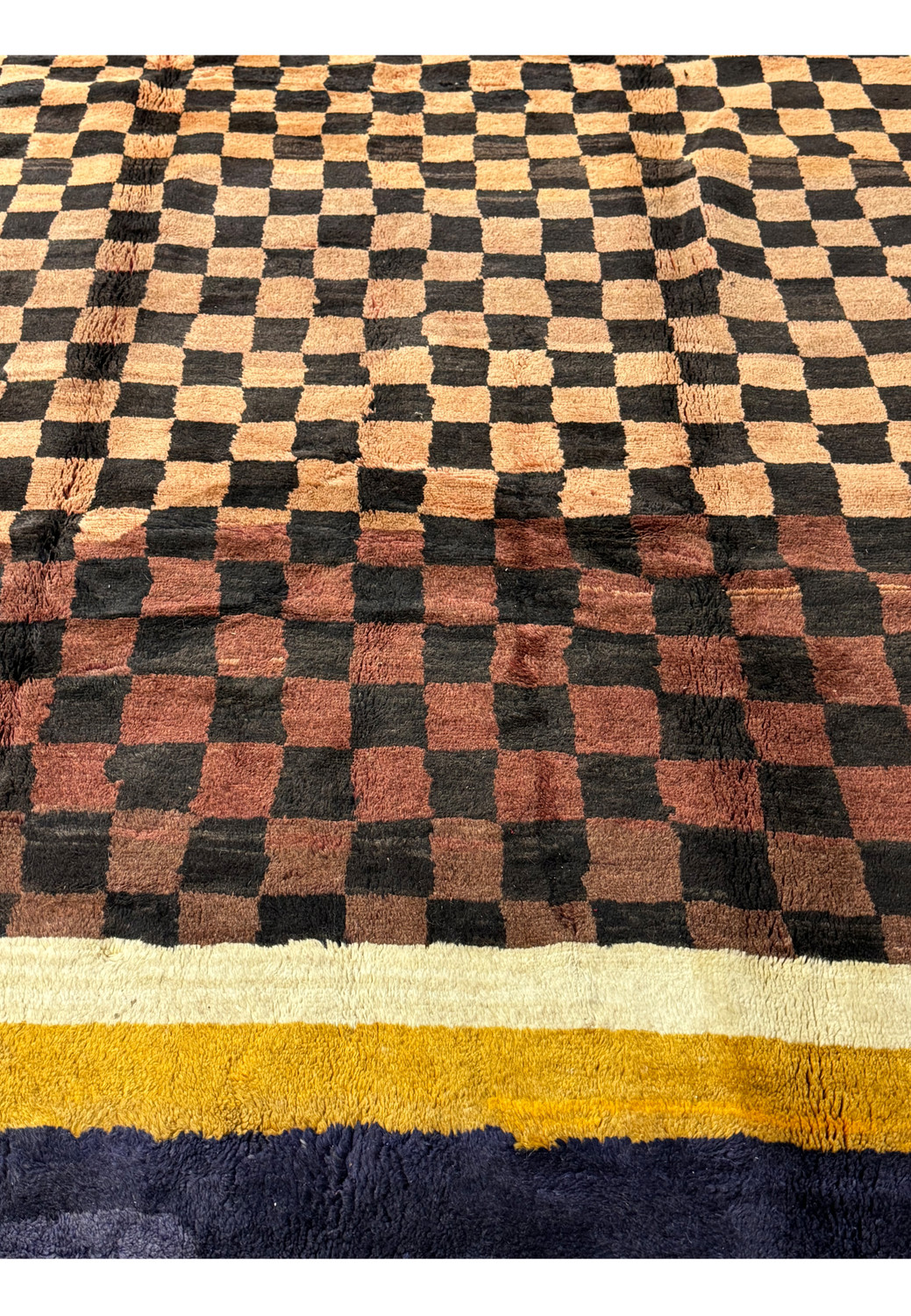 Close-up of the Nepal rug displaying the rich indigo and golden yellow border with a fringe, complementing the checkerboard pattern.