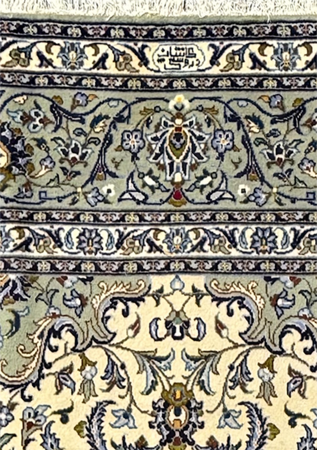 Zoomed-in view of the Persian Kashan rug showing the fine details of the weaver's signature within the ornate border