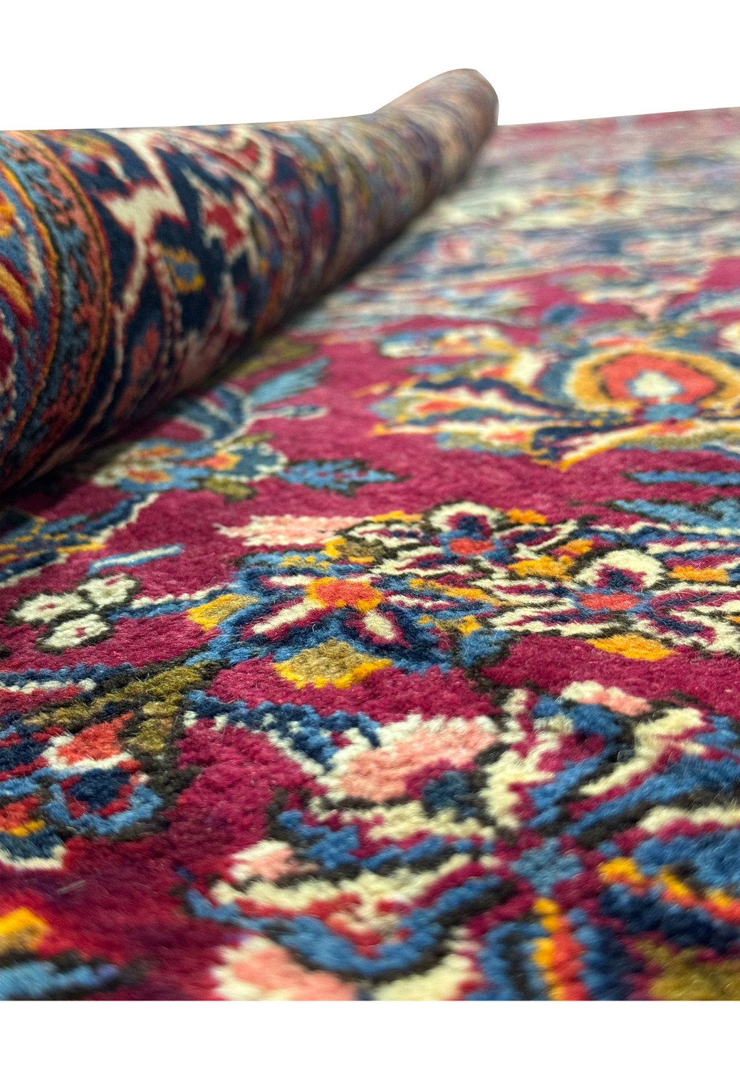 Close-up texture of a Persian Kashan rug showcasing the intricate weave and vibrant color details on a burgundy background.