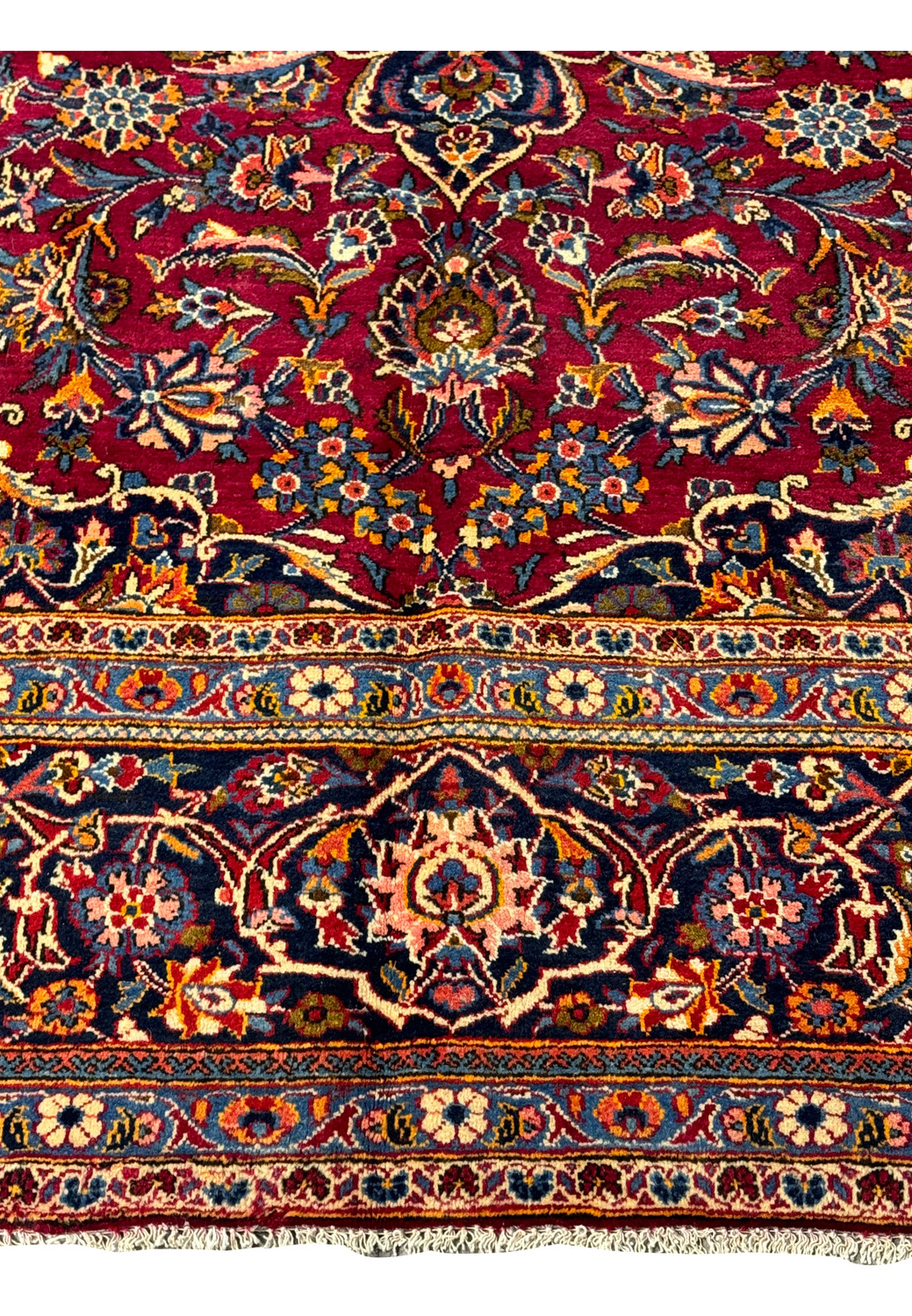 Corner detail of the Persian Kashan rug, where the opulent border meets the vibrant, patterned field.