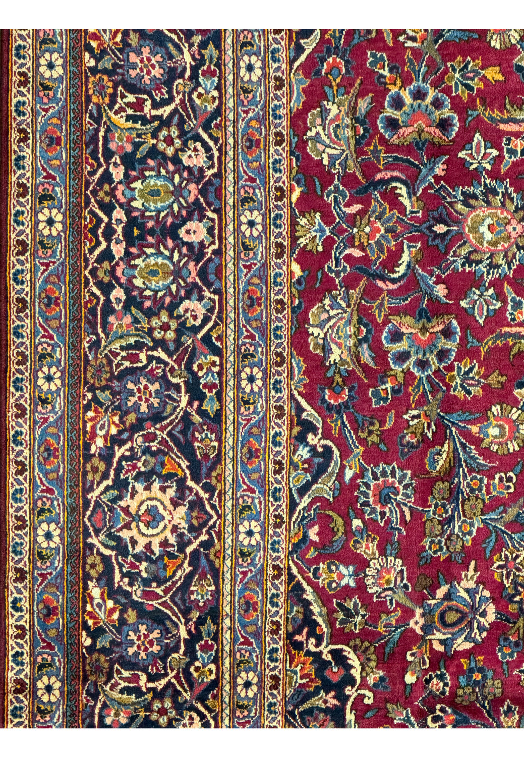 Detailed section of a Persian Kashan rug showing the exquisite border design with floral and geometric motifs.