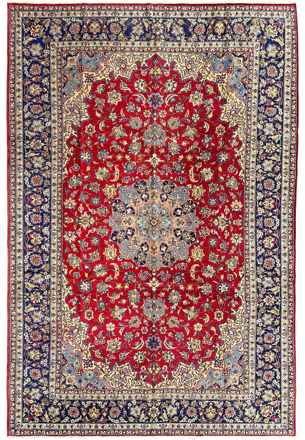 An overhead view of a traditional Persian Isfahan rug with a deep crimson field and a central floral medallion surrounded by intricate designs and motifs in indigo, cream, and gold, with a detailed navy blue borde