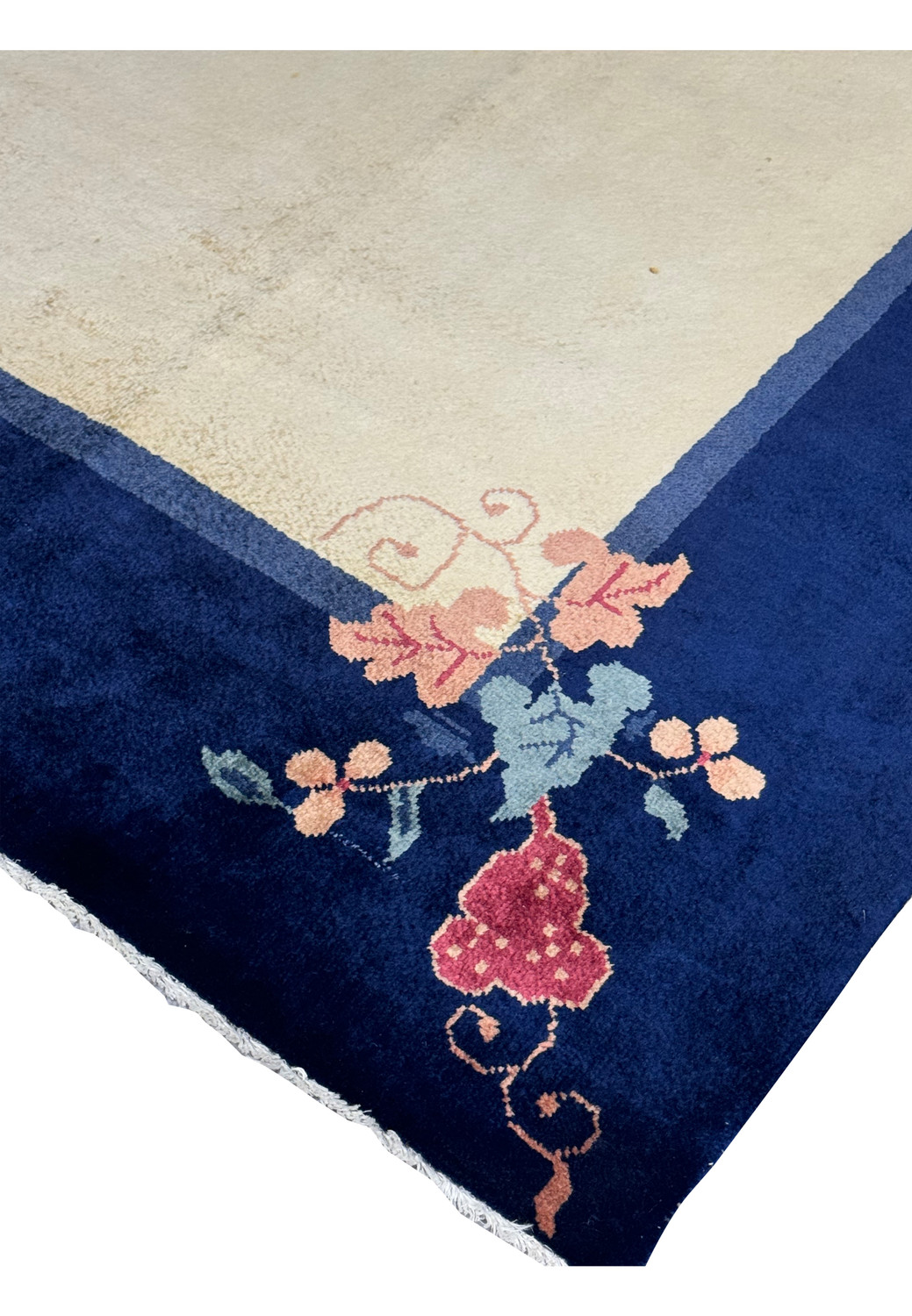 Angled close-up showing the texture and thickness of the vintage Art Deco rug with a navy border and beige center