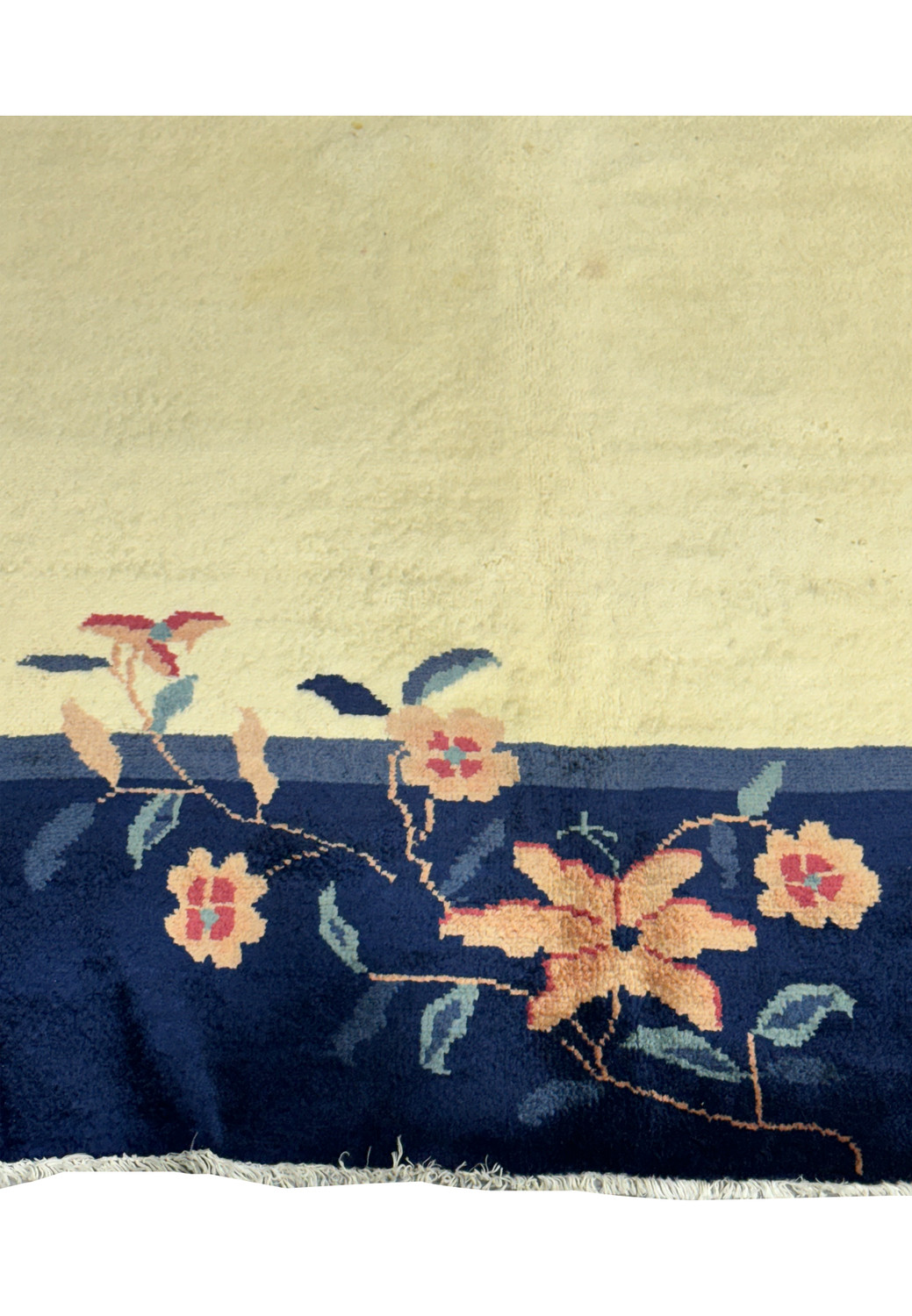 Detailed close-up of the navy blue border and corner floral designs on a vintage Art Deco rug against a beige field
