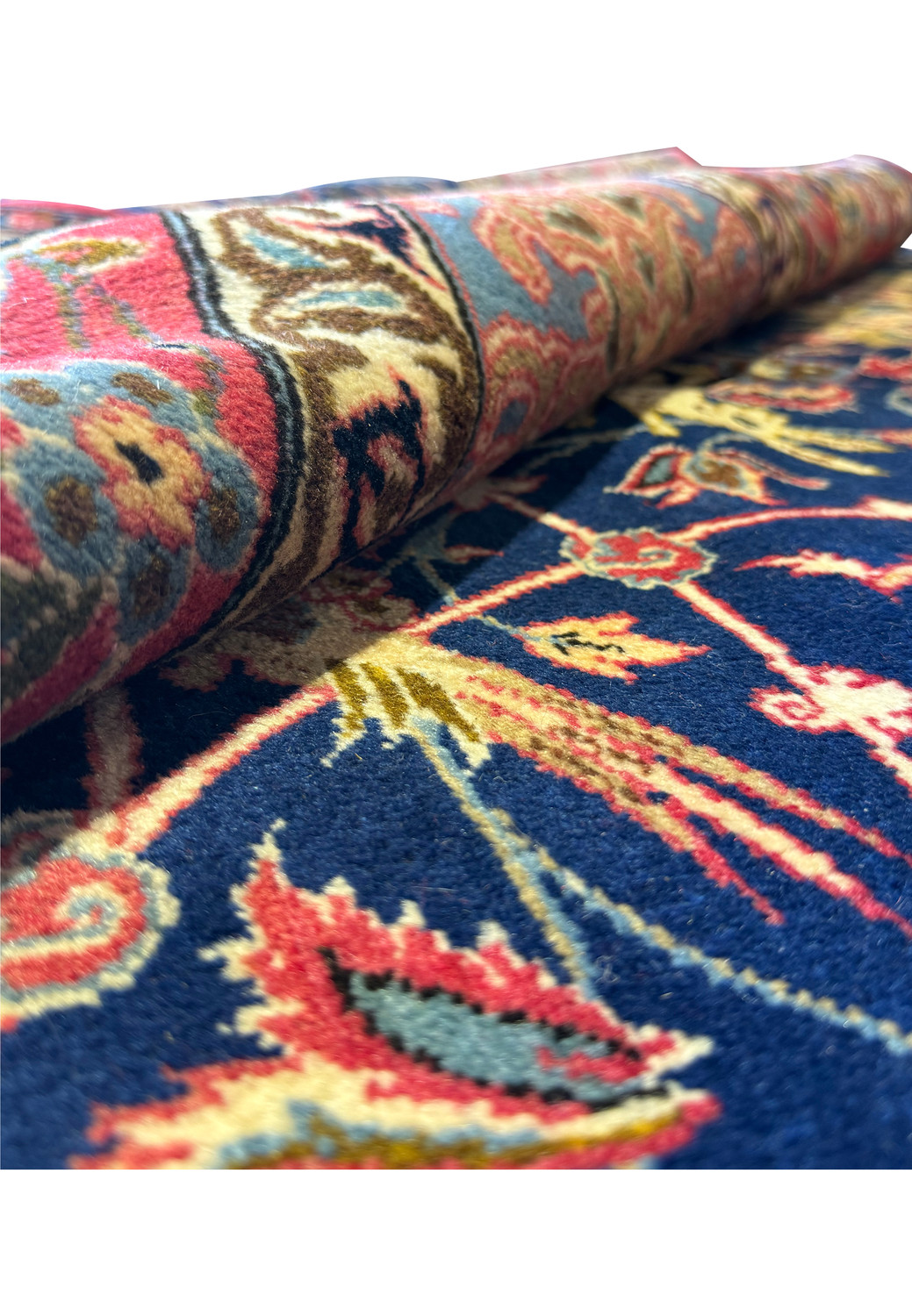Rolled Persian Isfahan rug highlighting the plush texture and detailed patterns with a glimpse of the rug’s underside.
