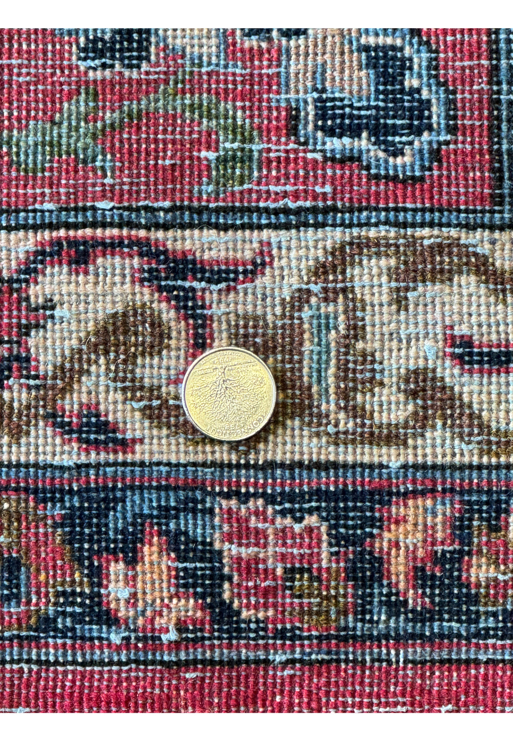image displaying the dense weave and fine knotting of a Persian Isfahan rug's underside with a coin for scale.