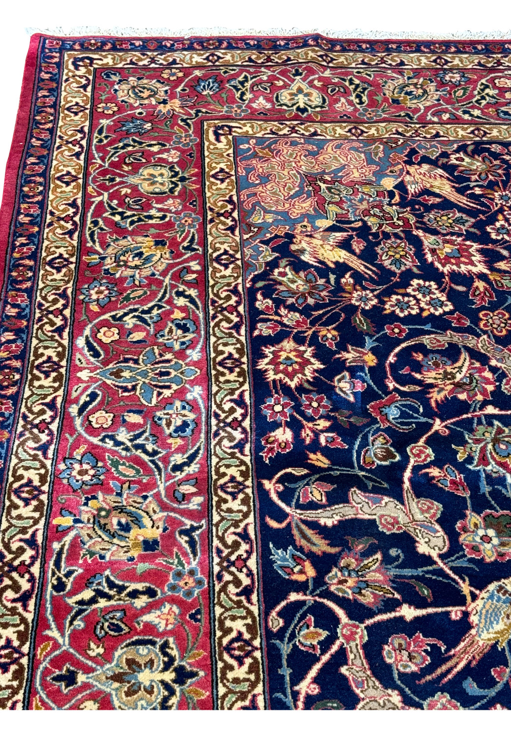 Detailed view of a Persian Isfahan rug featuring animal and floral patterns in vibrant colors against a navy background.
