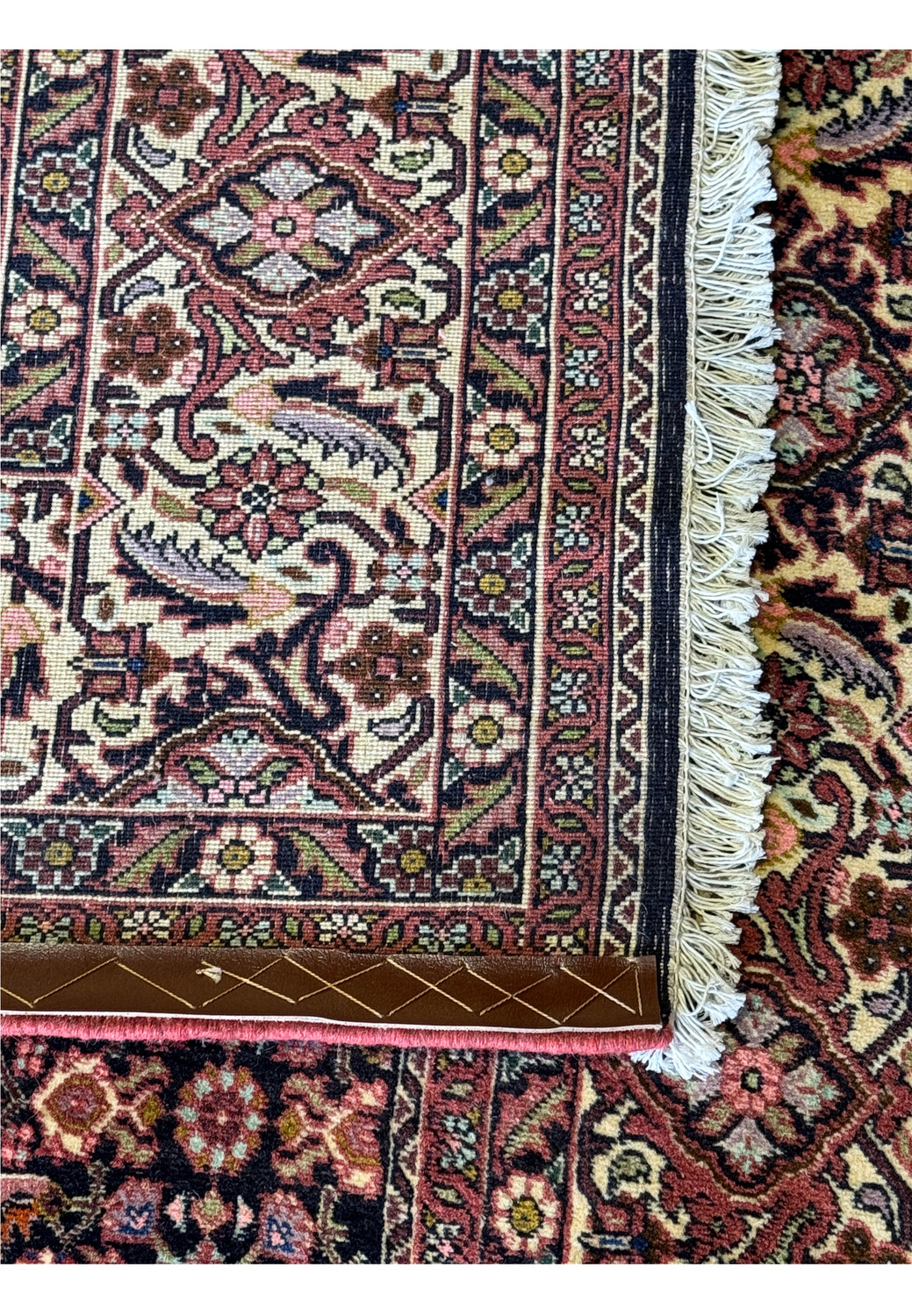 Corner section of a Persian Bijar rug illustrating the transition from the richly decorated border to the dense floral pattern of the field