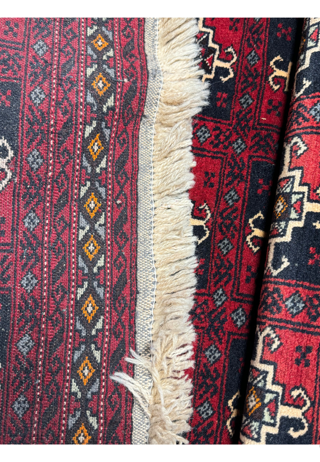 Backside of the 3x5 Baluch rug, showing its thickness and the edge finishing, demonstrating the rug's sturdy construction.
