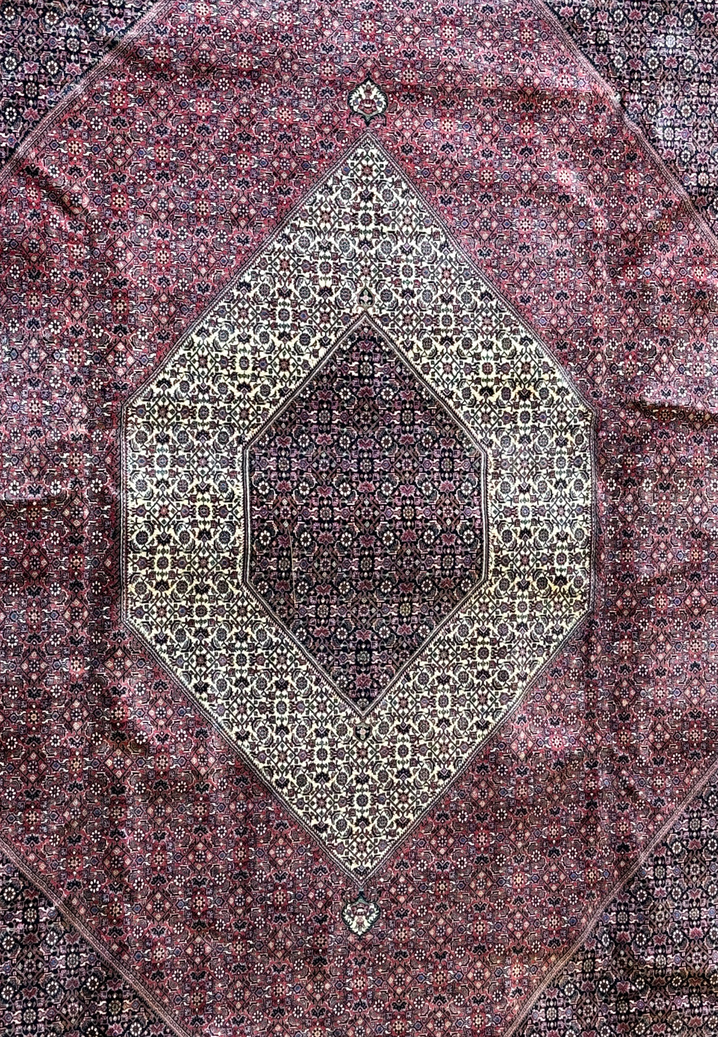 Close-up of the central medallion of the Persian Bijar rug, highlighting the precision of the herati patterns in a rich array of burgundy and navy