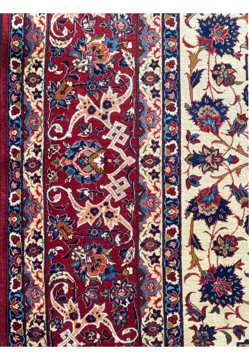 Detailed view of the rug's elaborate border of the Persian Isfahan rug with floral and geometric patterns on a red background.