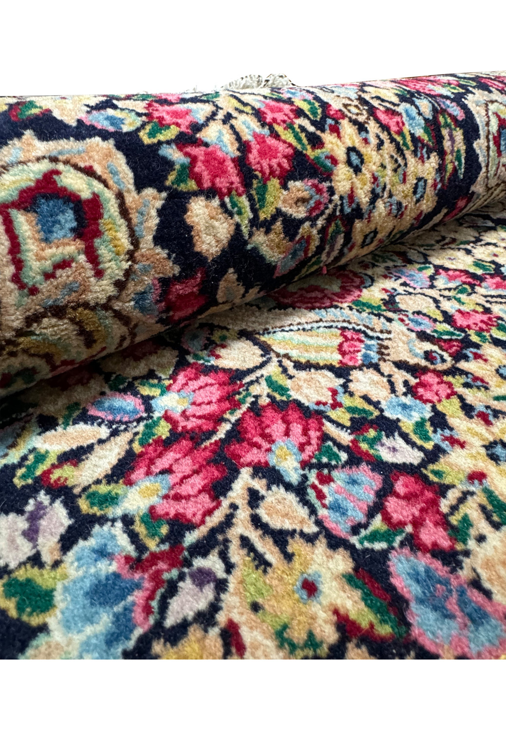 Perspective view of a rolled Persian Kerman rug, emphasizing the texture and compact weaving style