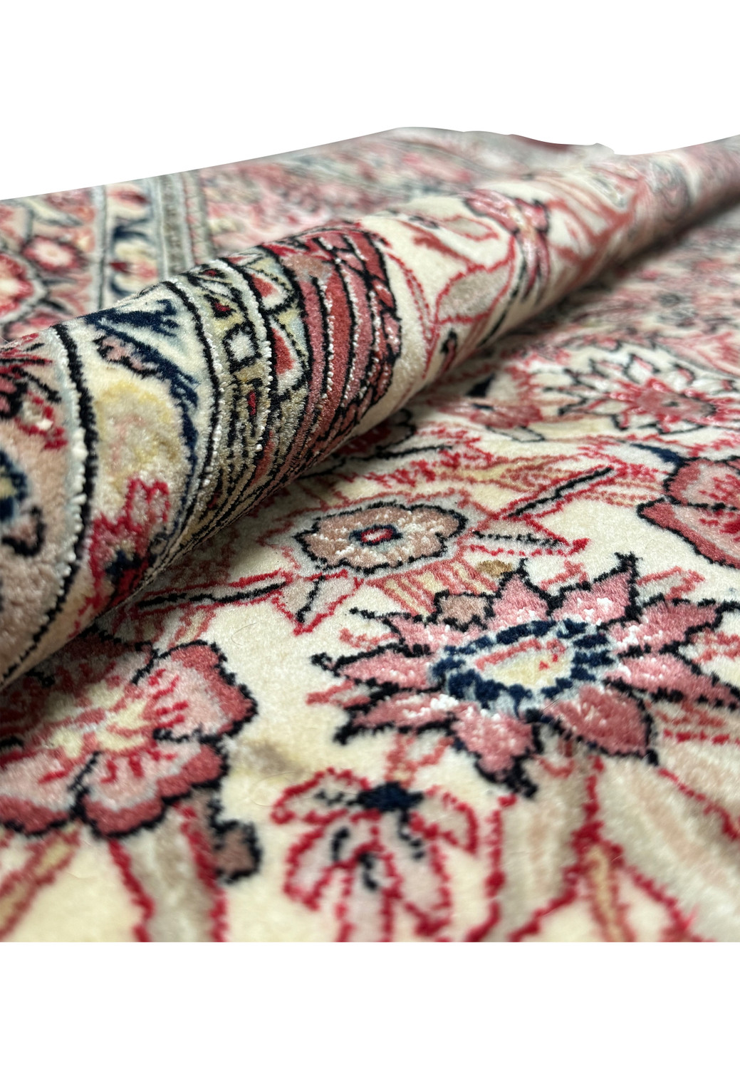 Another view of the folded Persian Qum rug, displaying the tightness of the weave, the plushness of the wool, and the intricate details of the patterns with silk highlights visible along the fold.