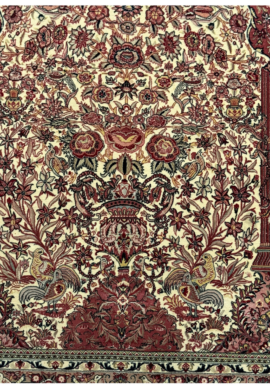 Close-up of the central design of the Persian Qum rug, focusing on the detailed floral medallion and the vibrant contrast of reds and creams with silk highlights.