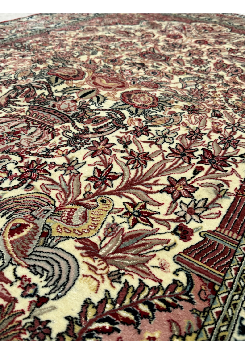 Perspective shot of the Persian Qum rug, focusing on the intricate details of the floral patterns and animal motifs, showcasing the fine silk accents and the plush texture of the wool pile.