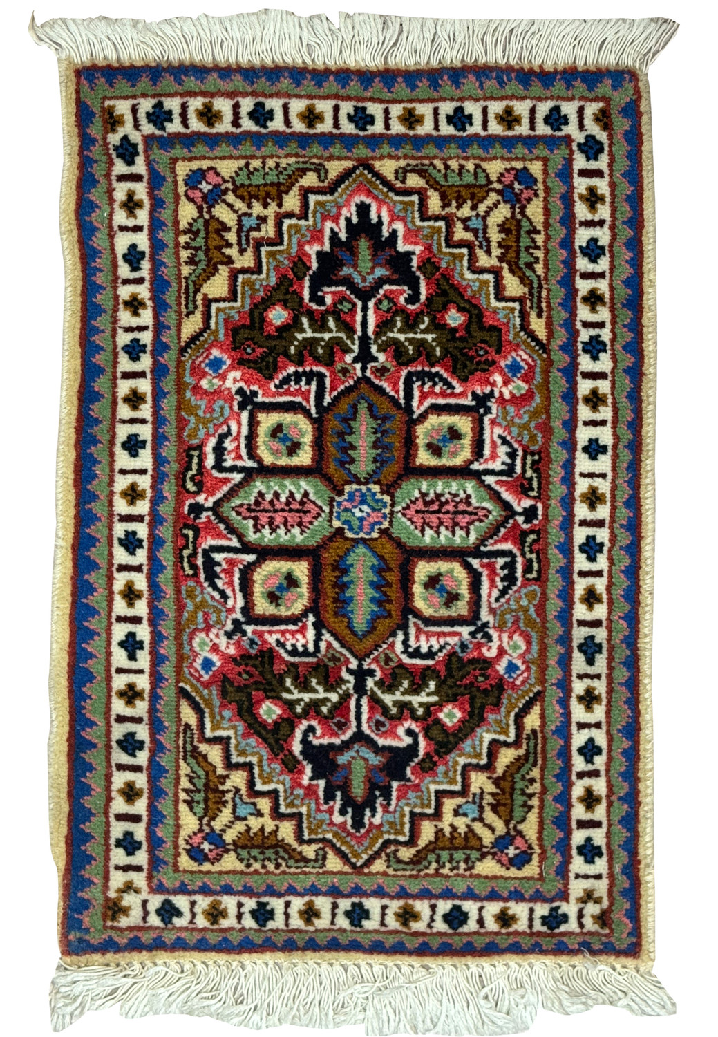 An overhead view of a small Persian Tabriz rug with a central medallion design, featuring intricate patterns in deep blue, red, and green on a beige background, framed by a detailed border and white fringe