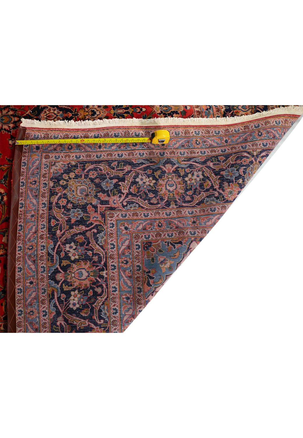 A shot of the Persian Kashan rug with a measuring tape across it, providing a scale to understand the knot density and high quality of the rug