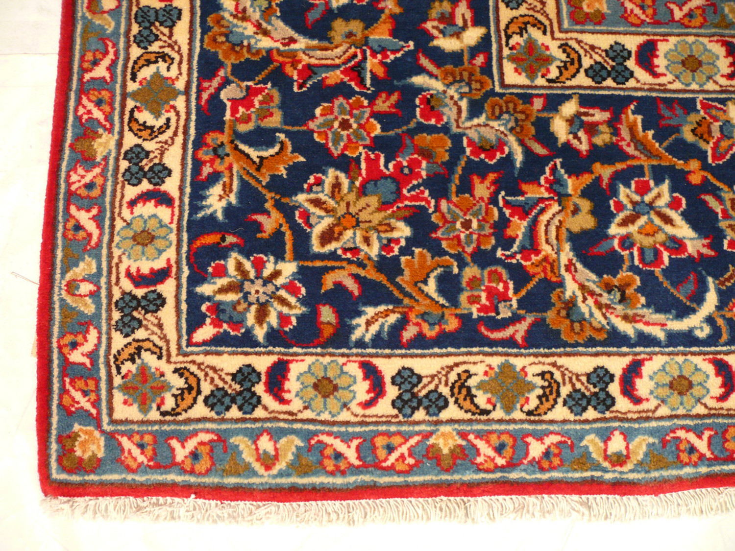 Enhanced close-up of the Persian Isfahan rug's decorative border with a deep focus on the precision of the small floral and vine elements, set against a dark blue background.