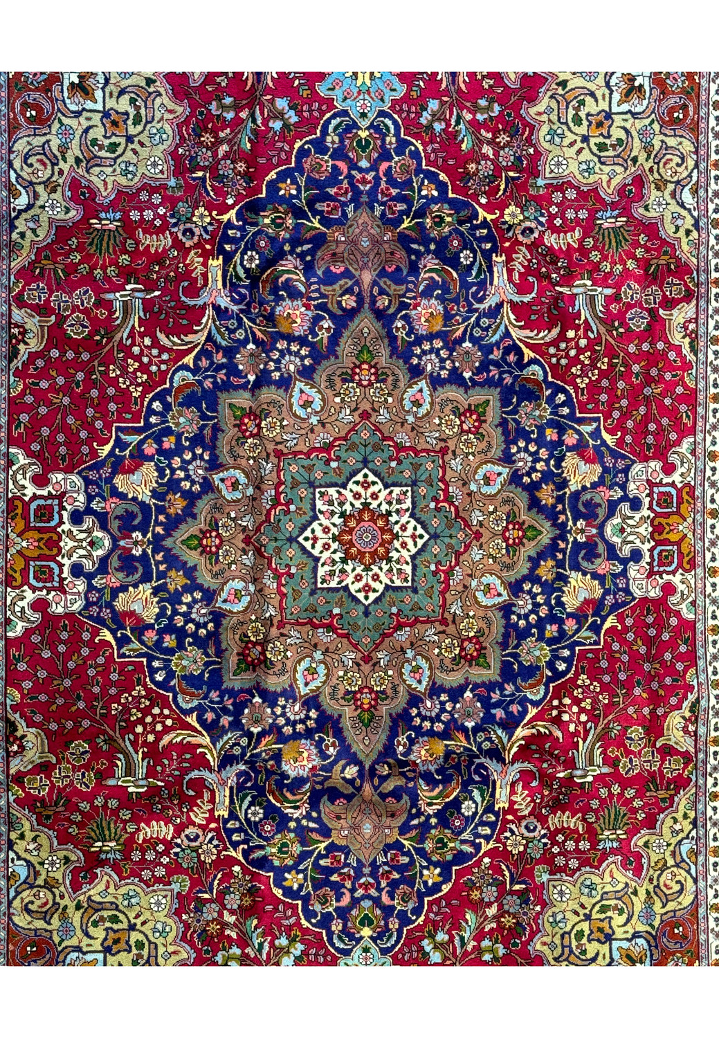 Close-up of the Persian Geometric Tabriz Rug's central medallion with intricate designs in sage green, pink, and orange on a navy blue background.