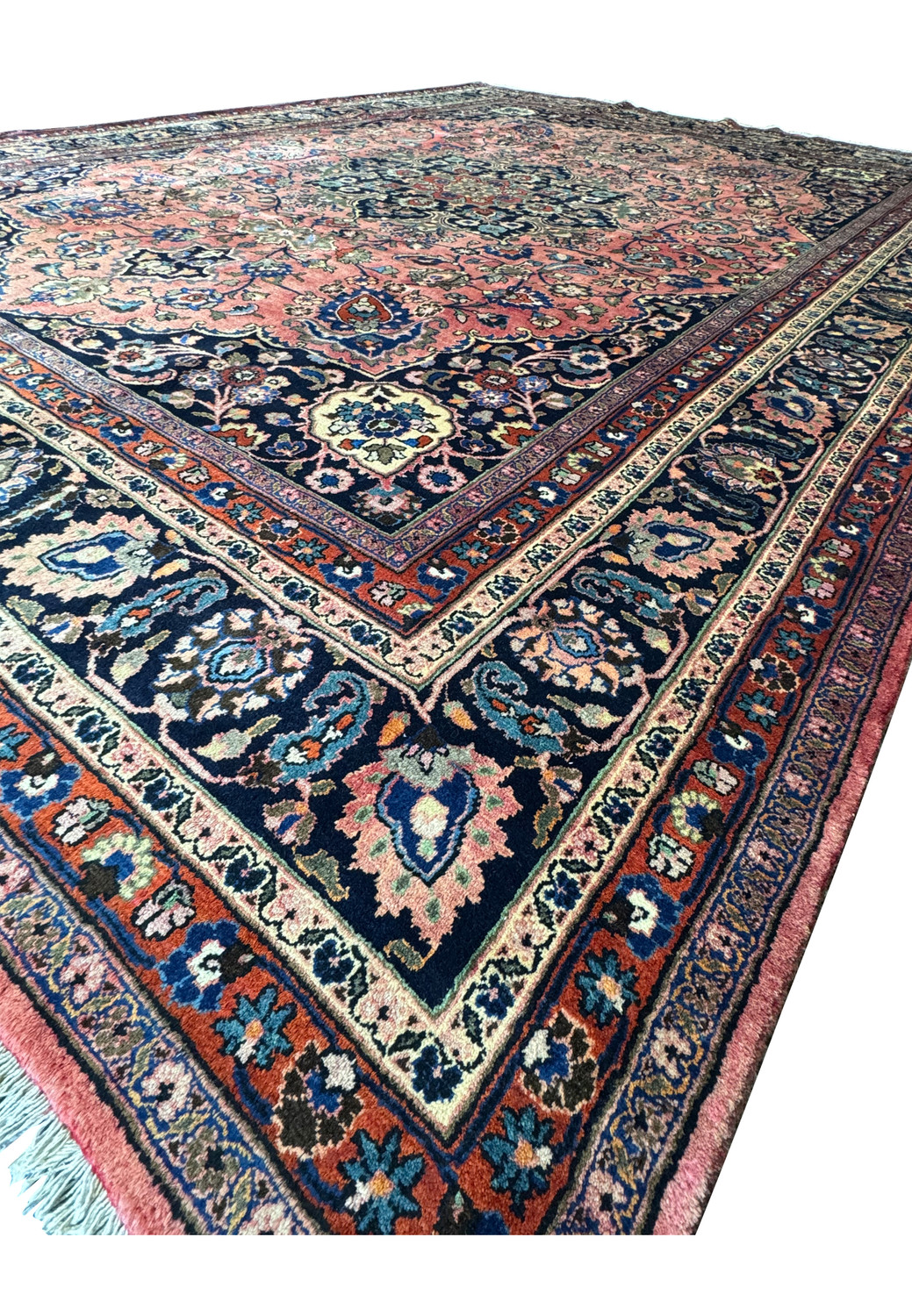 Oblique angle view of the 10x13 Persian Mashad rug, emphasizing the rug's plush pile and intricate edging.