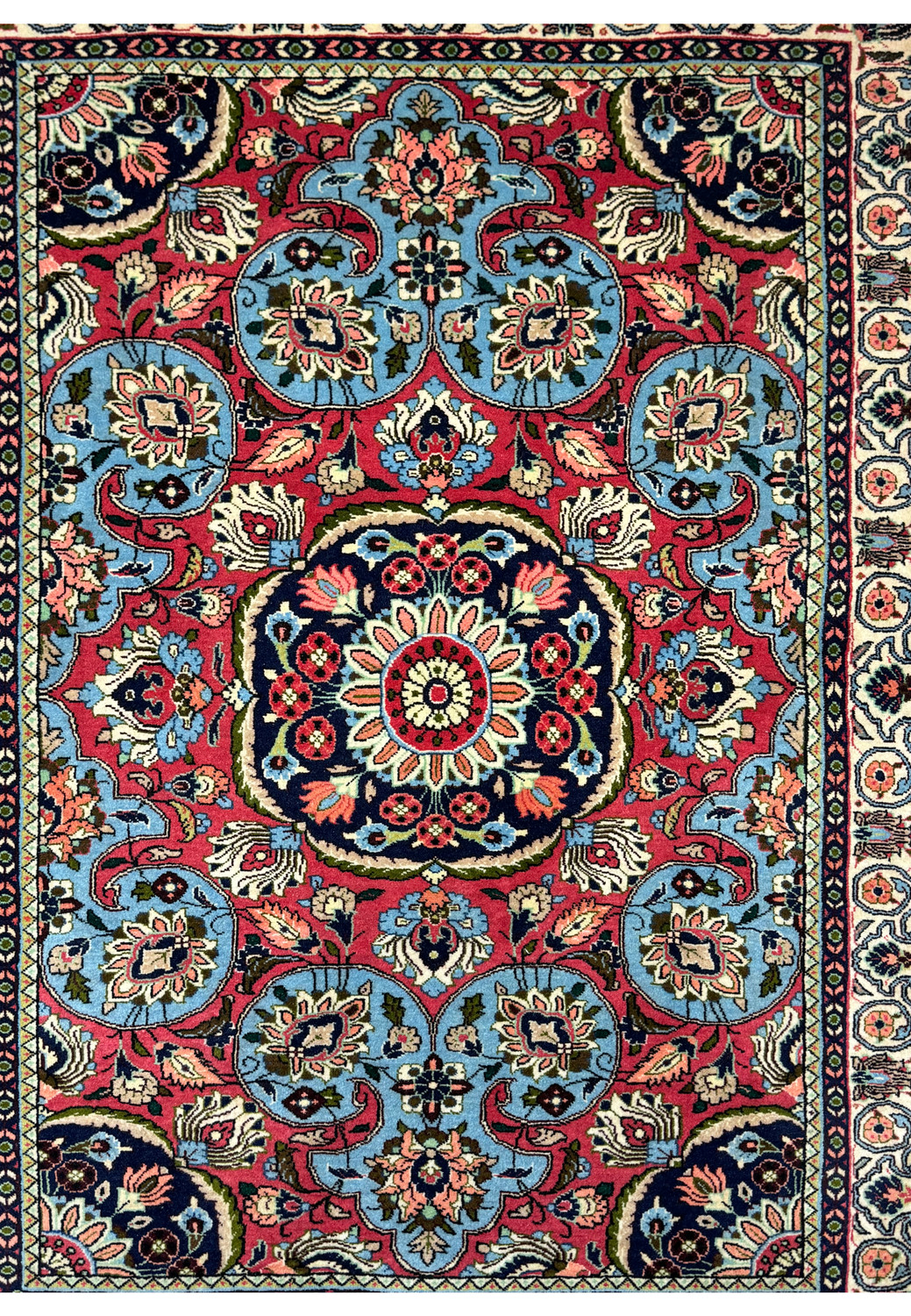 Close-up view of a Persian Bijar rug's central medallion in cerulean blue and red with detailed patterns, showcasing the high-density knotting technique of traditional Persian rug-making