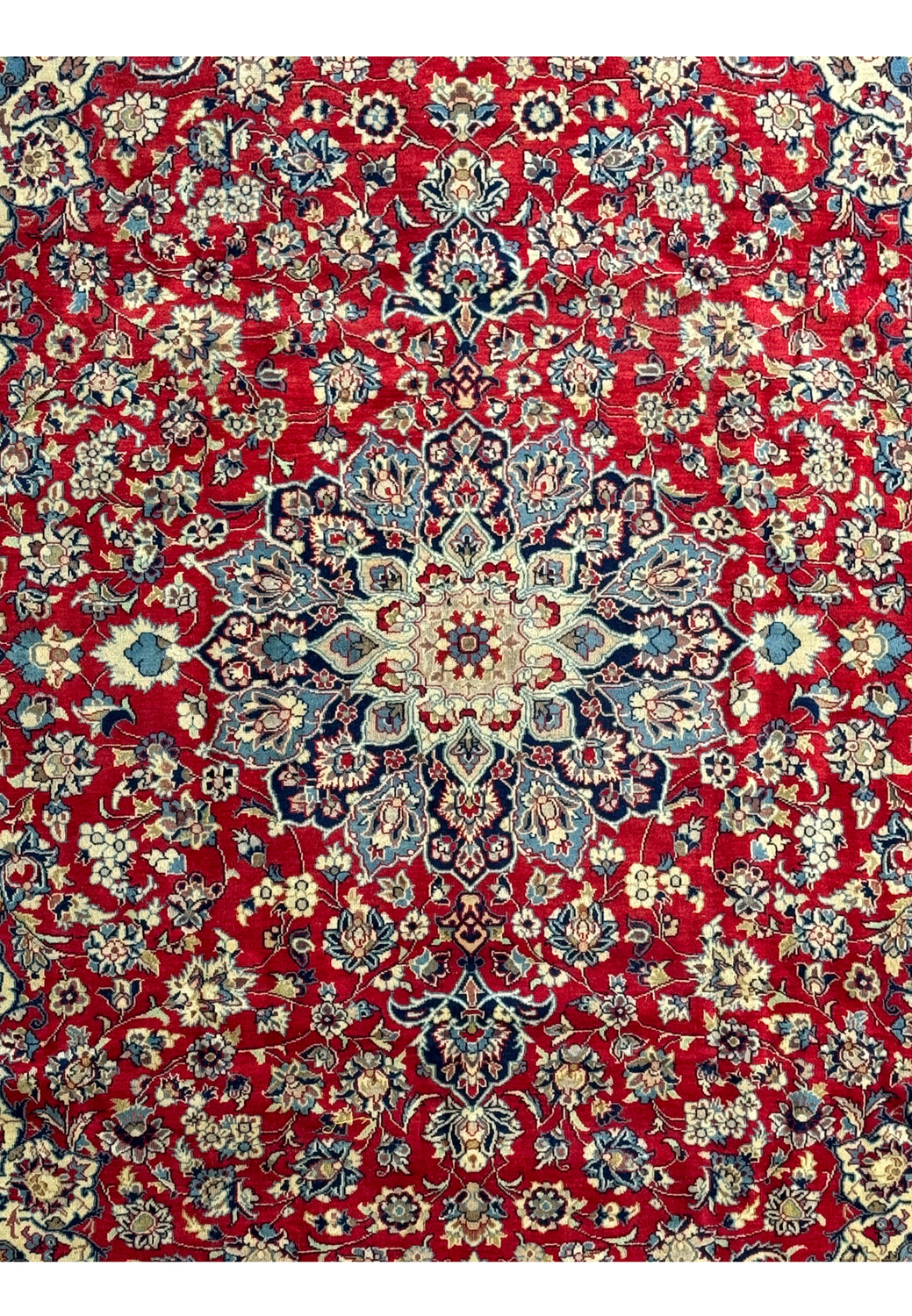 A detailed image of the 10 x 13 Persian Isfahan Rug's border, emphasizing the deep navy background adorned with intricate floral patterns in shades of ivory and blue. The craftsmanship is highlighted in the precise and symmetrical design, which frames the vibrant red center and enhances the overall elegance of the rug.