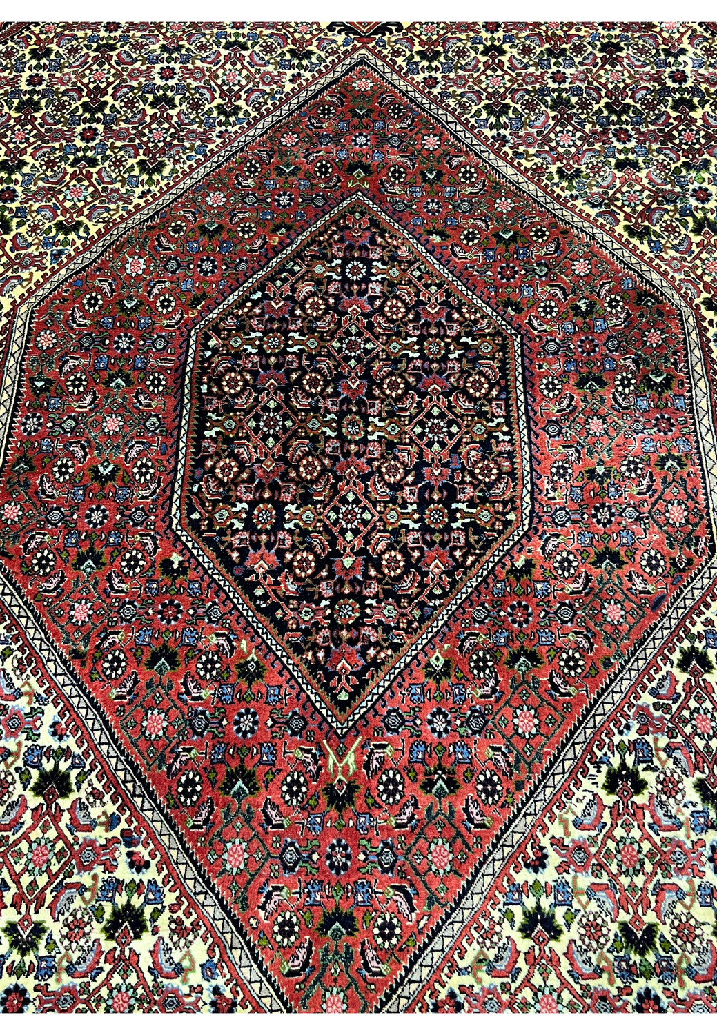 Close-up of the medallion on a 9.8 x 12.2 Persian Bijar rug highlighting precise knot work, deep saturated reds, navy outlines, and crisp geometric symmetry.