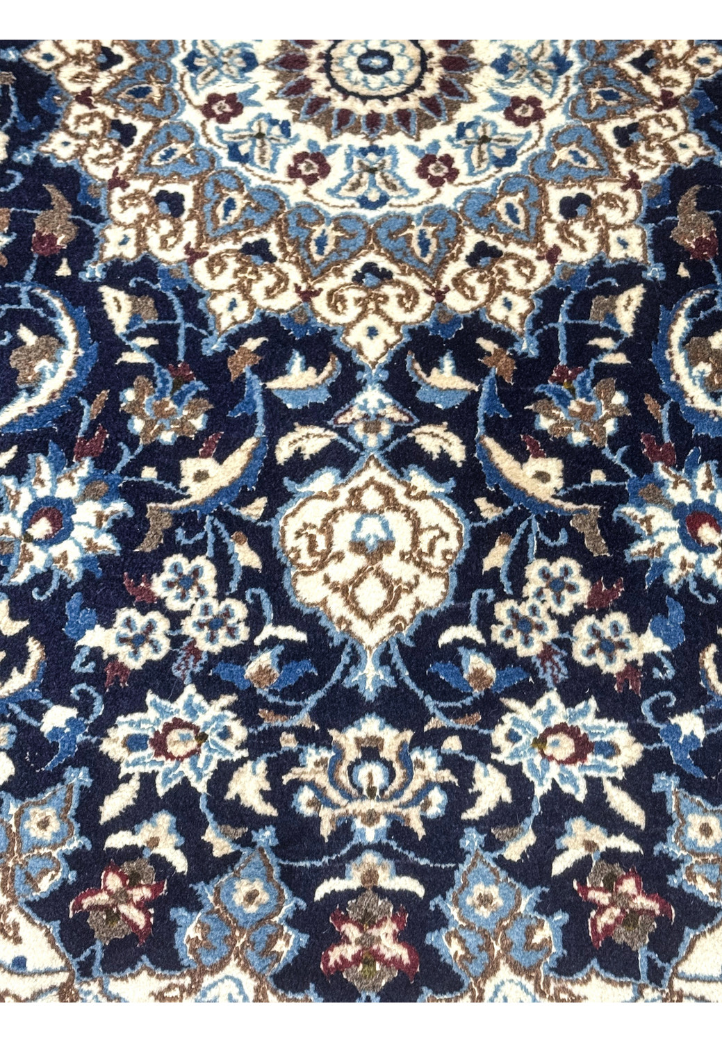 Detail of floral motifs on navy background of handmade Persian rug