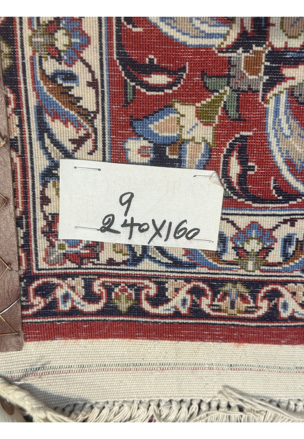 Backside of Persian Isfahan Seirafian rug showing tight hand-knotted weave and intricate red and the tag showing the metric size.