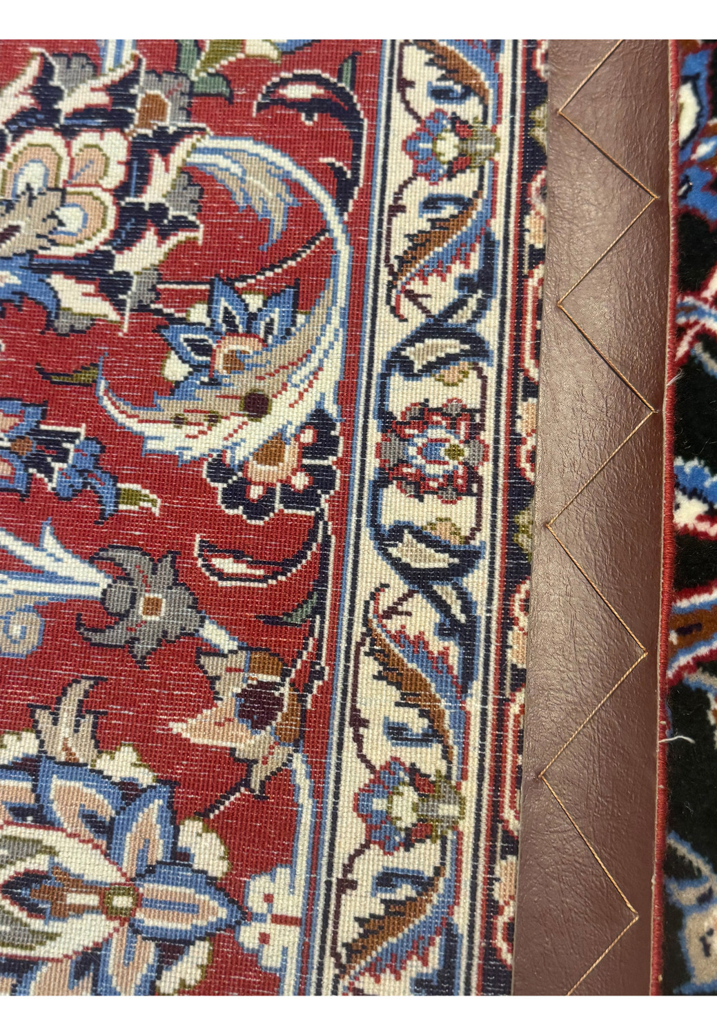 Backside of Persian Isfahan Seirafian rug showing tight hand-knotted weave and intricate red and ivory floral motifs.