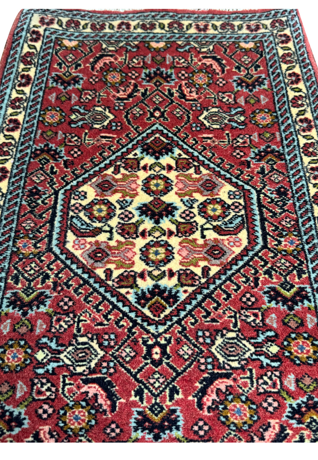 Closeup of ivory diamond medallion on 1'6 x 2'2 Bijar Poshti Persian rug with detailed floral motifs and rich red field.